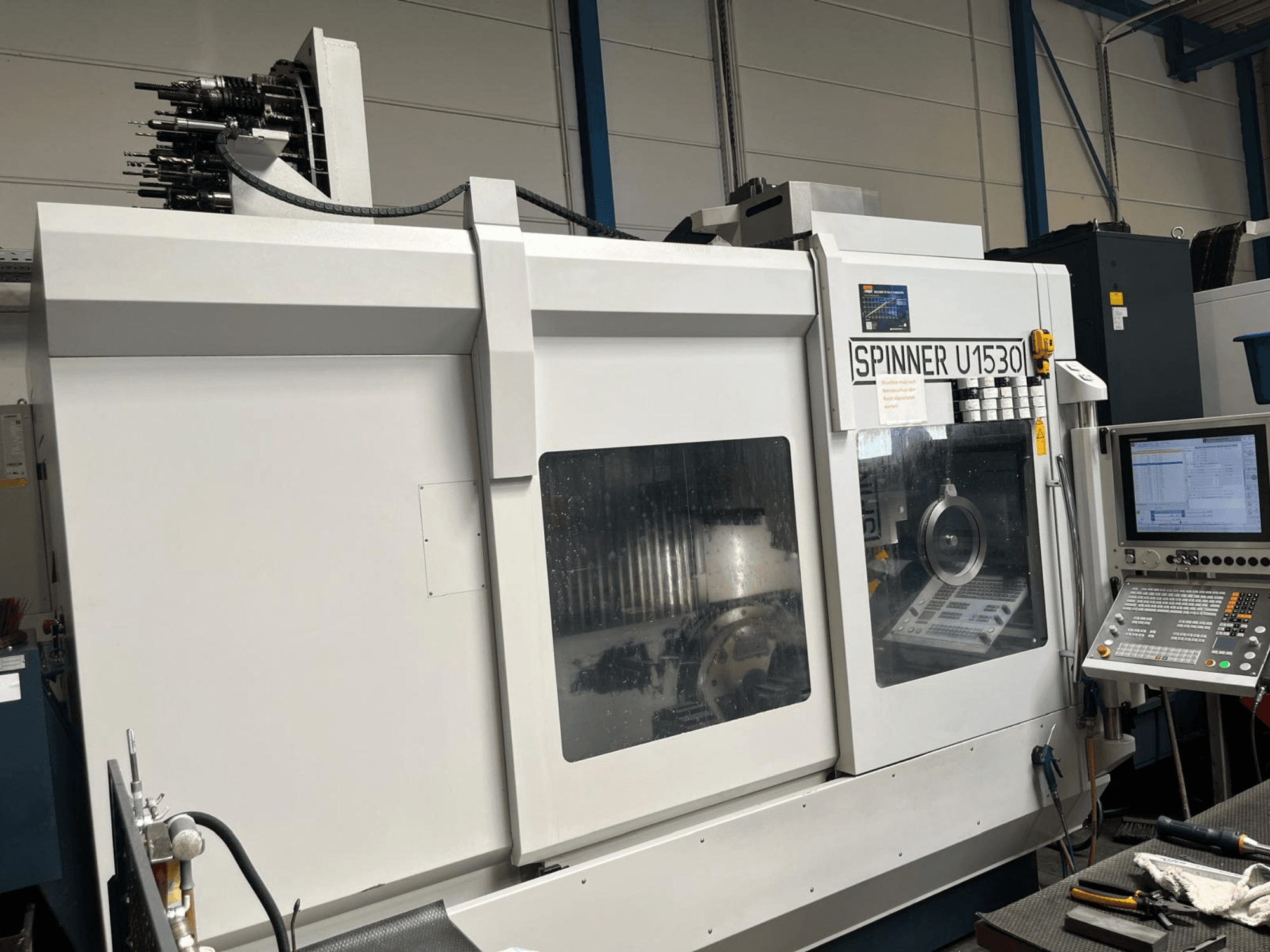 Centro di lavorazione verticale SPINNER U1530, vista frontale che mostra il pannello di controllo e il sistema di utensili nella parte superiore.
