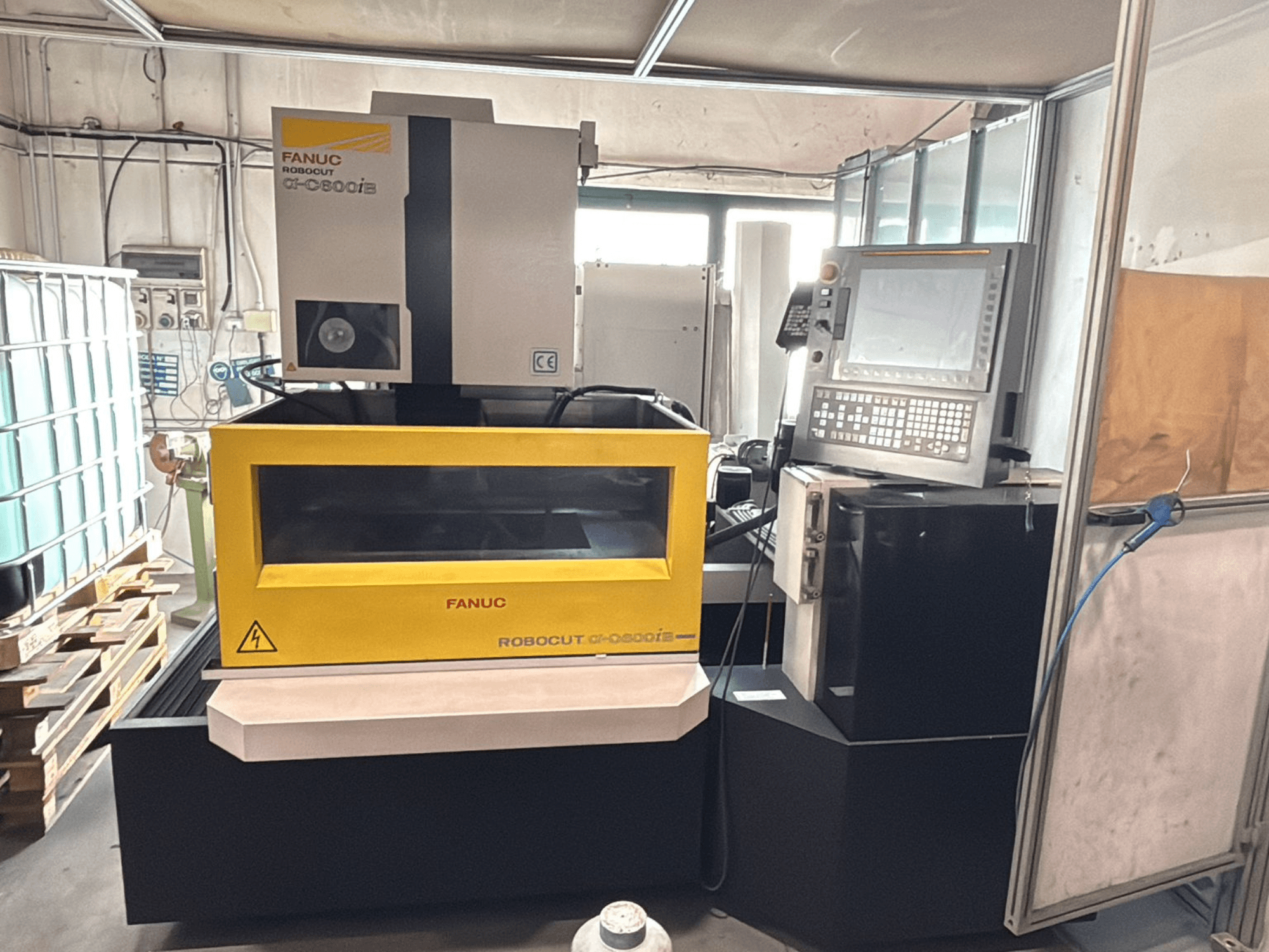 Vista frontale di una macchina CNC FANUC Robocut α-0iE con involucro giallo, che mostra il pannello di controllo e il display.