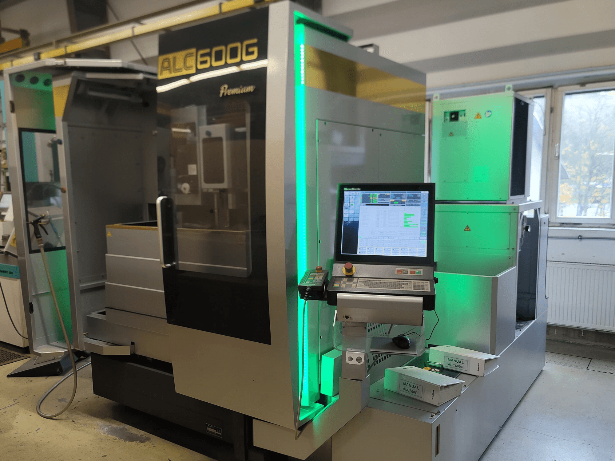 Macchina per elettroerosione a filo Sodick ALC600G Premium, vista frontale, con pannello di controllo e dettagli esterni illuminati.