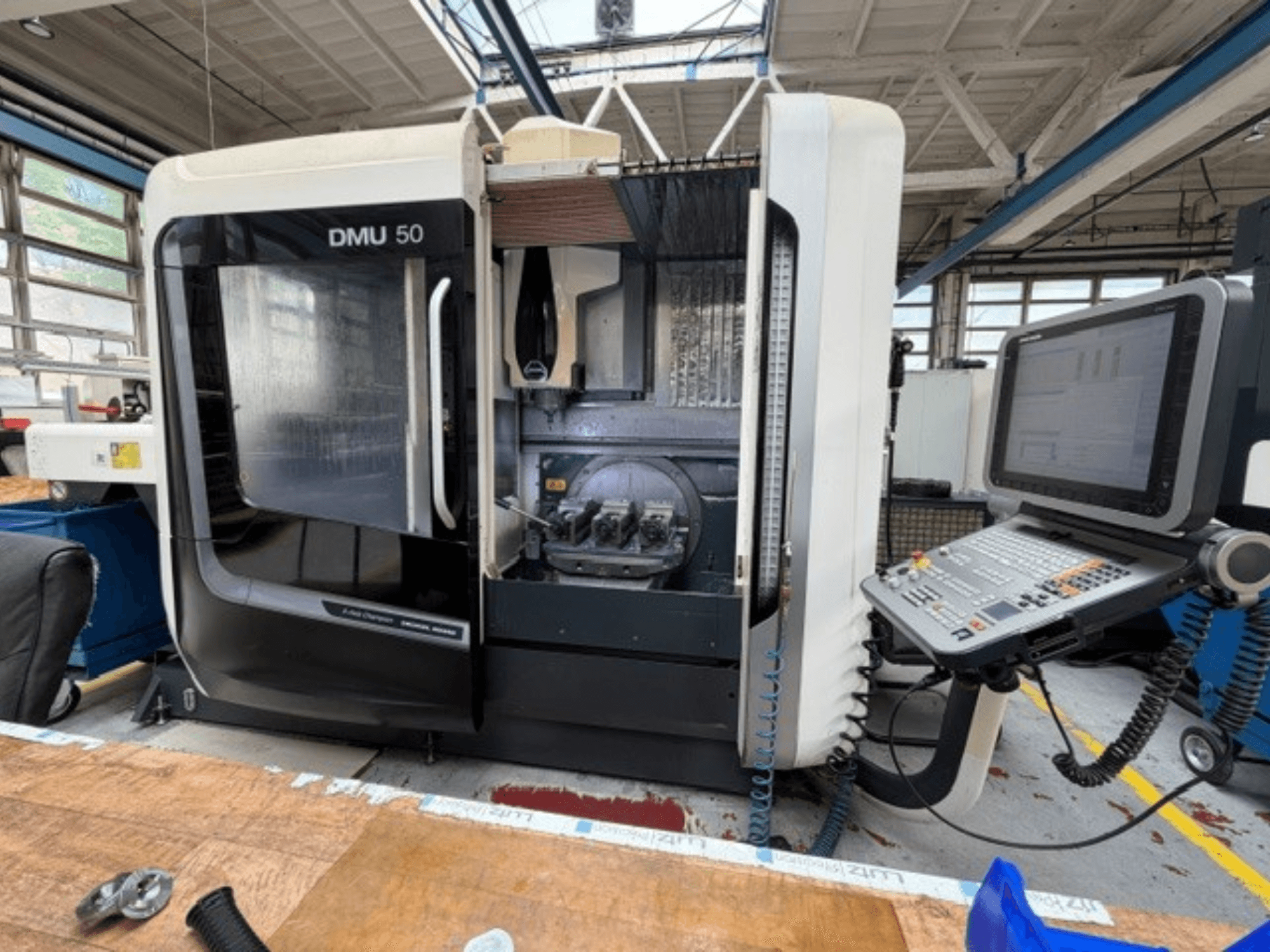 Centro di lavorazione verticale DMG MORI DMU 50 di terza generazione visto frontalmente, con lo sportello aperto, il pannello di controllo CNC visibile e l'area di lavoro all'interno.