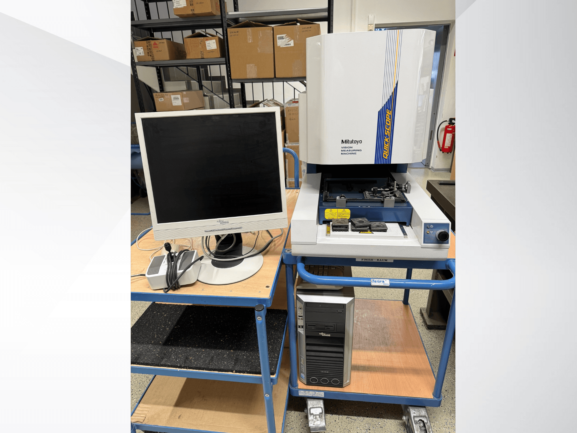 Macchina di misura visiva Mitutoyo Quick Scope con monitor, PC e accessori, vista frontale, su un carrello blu.