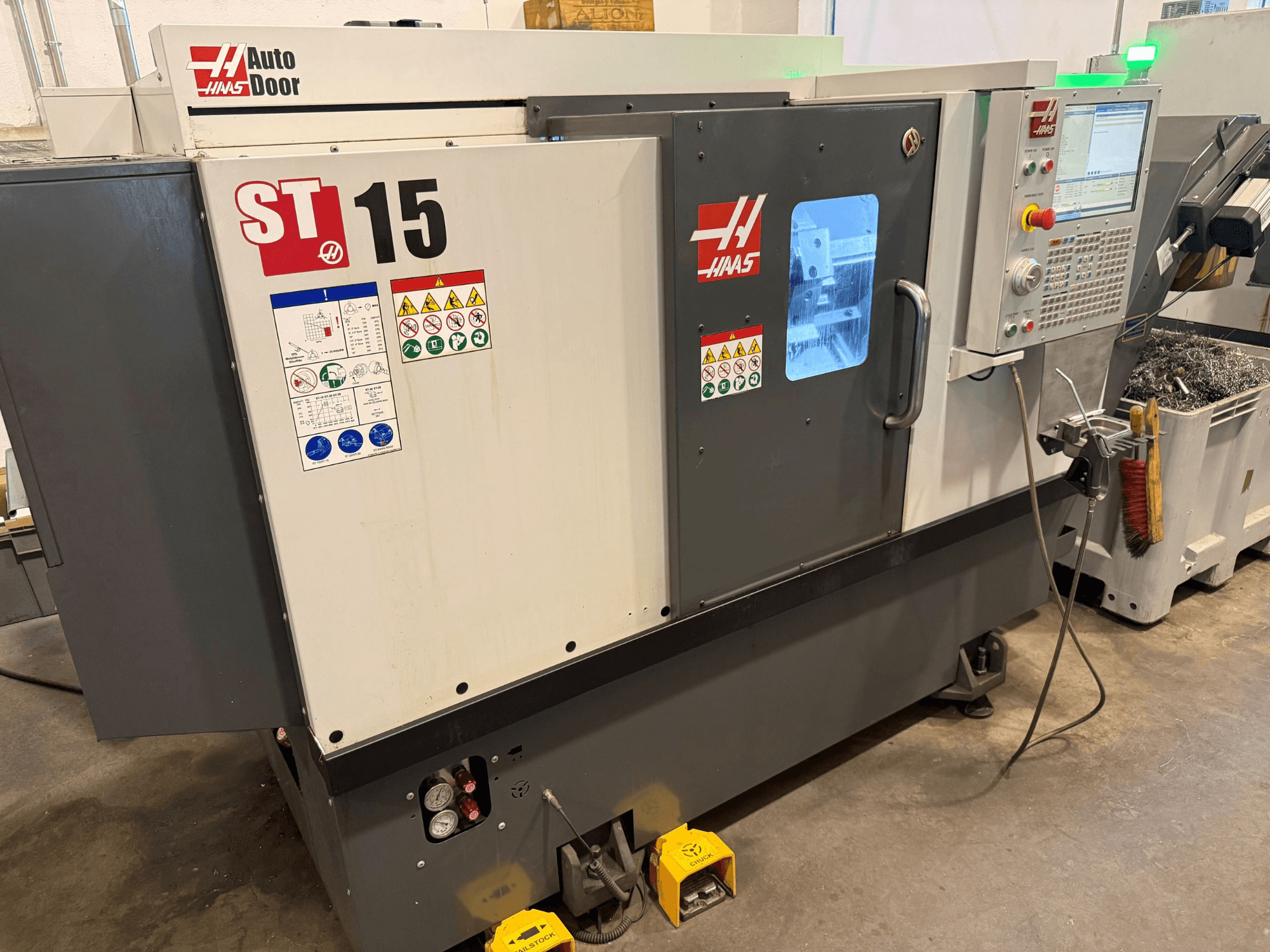 Tornio orizzontale HAAS ST 15, vista frontale che mostra il pannello di controllo, lo sportello automatico e gli indicatori tecnici visibili.
