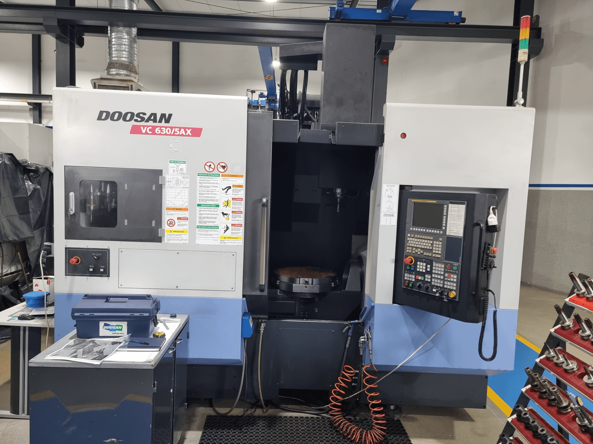 Centro di lavorazione universale DOOSAN VC 630/5AX, vista frontale che mostra il pannello di controllo, l'area di taglio e i dispositivi di sicurezza.
