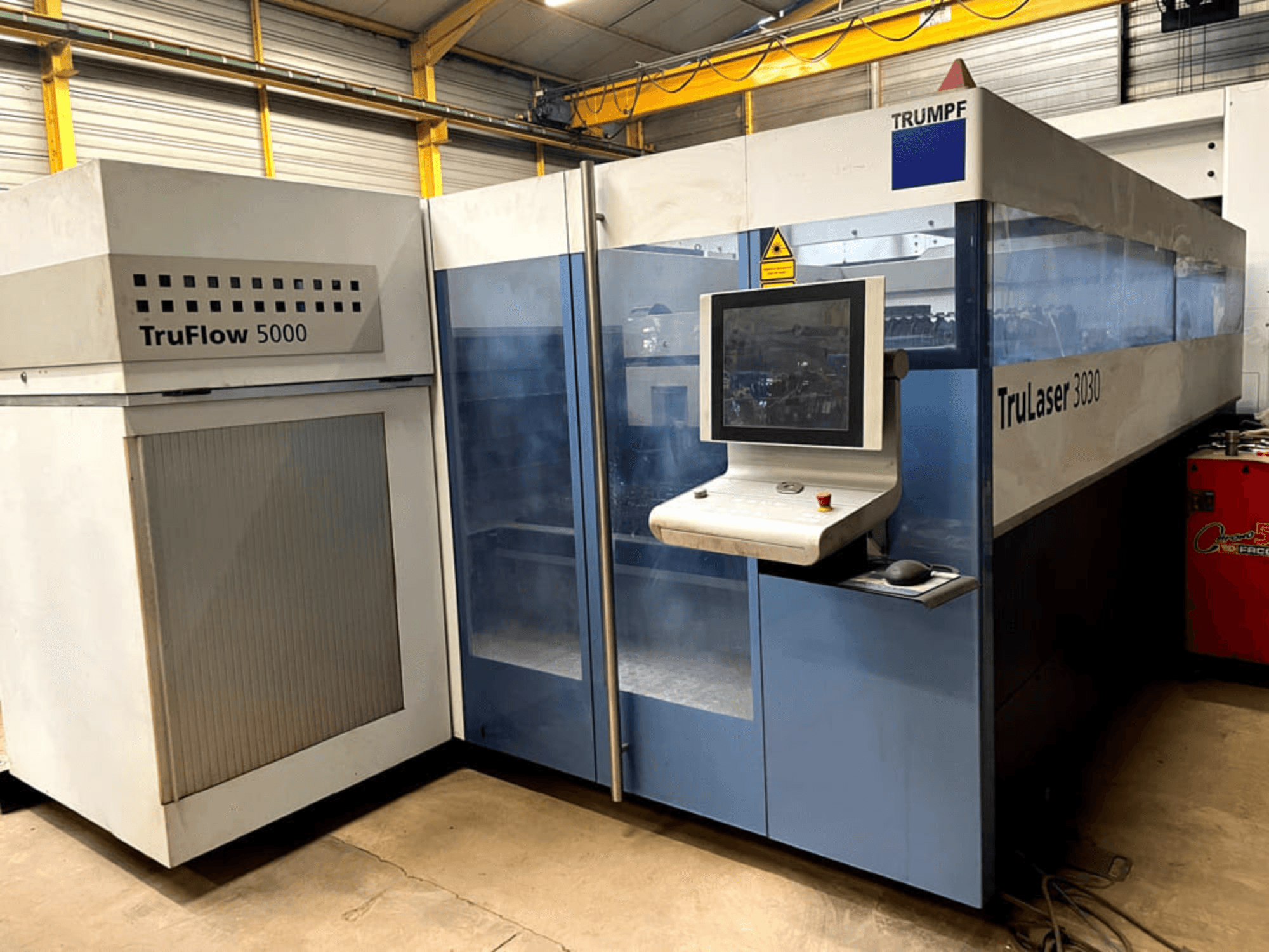 Macchina da taglio laser a CO₂ TRUMPF TruLaser 3030 vista frontale, con pannello di controllo e unità TruFlow 5000 adiacente.