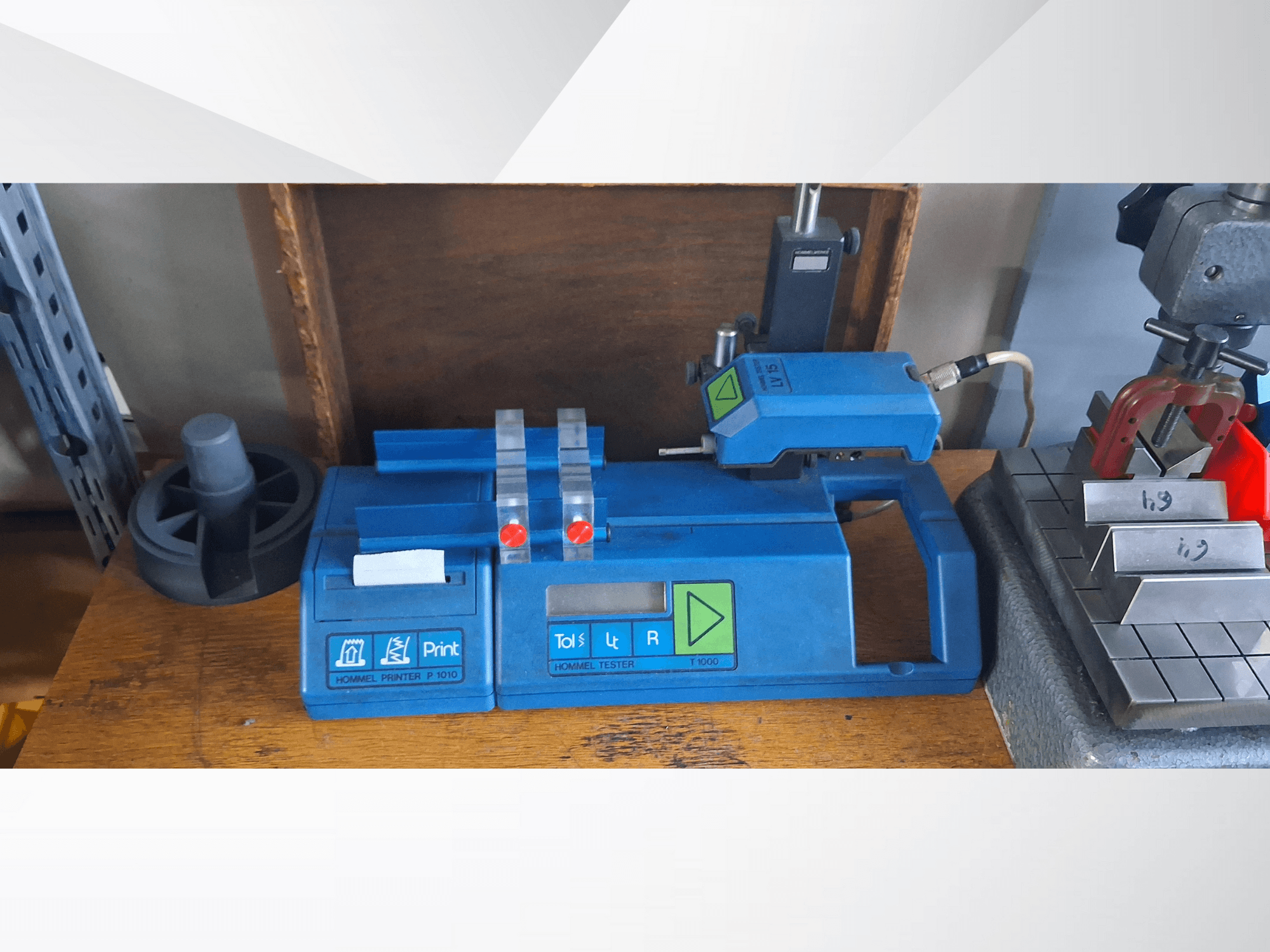 Stampante Hommel P 1010 e Tester T1000 in vista laterale, con involucro blu, pulsanti e indicatori rossi, su un banco di lavoro.