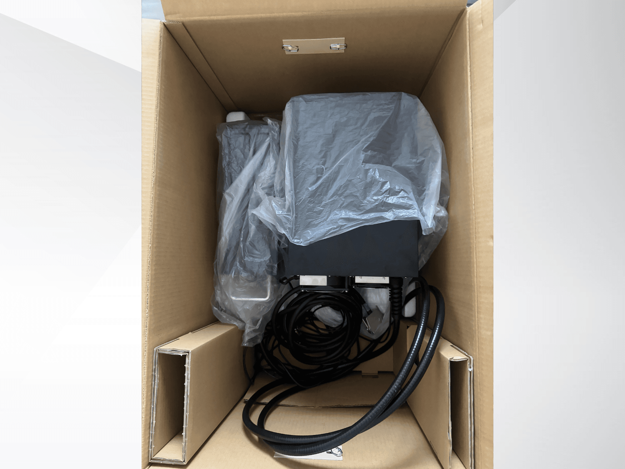 Macchina per la marcatura laser KEYENCE MD-X2500A in una scatola di cartone, parzialmente ricoperta di plastica, con cavi e componenti visibili.