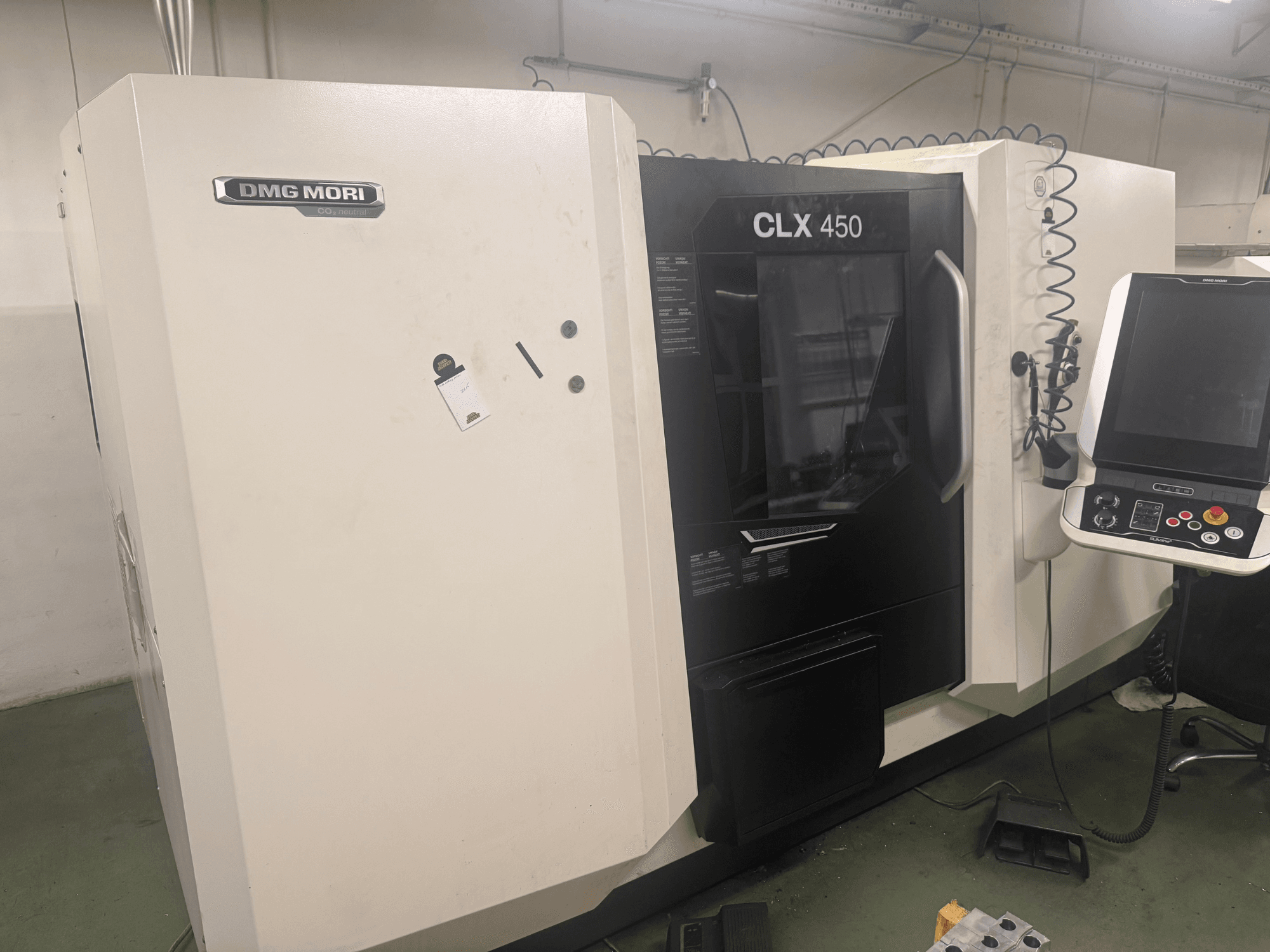 Macchina CNC DMG MORI CLX 450, vista laterale con pannello di controllo, pulsanti operativi visibili e spazio di lavoro pulito.