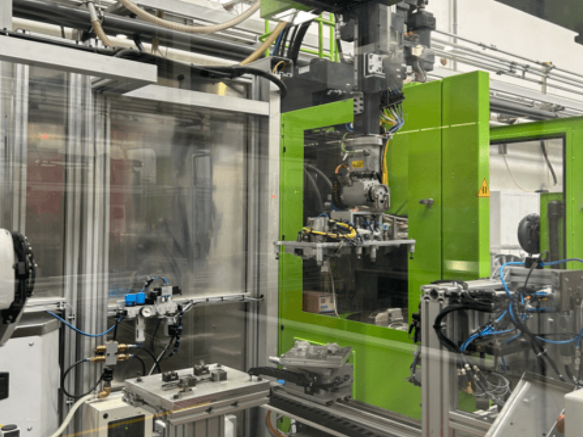 Macchinario industriale robotizzato in un involucro verde, che mostra i componenti meccanici e le tubazioni, visti frontalmente.