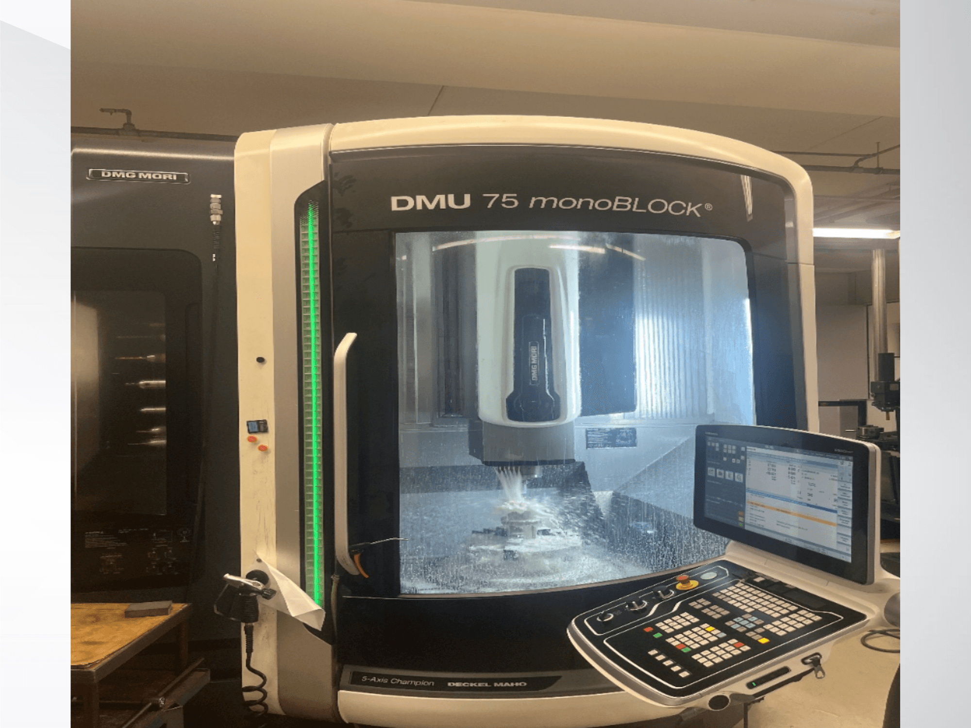 Centro di lavorazione universale DMG MORI DMU 75 monoBLOCK visto frontalmente, con in primo piano il pannello di controllo e l'area di fresatura.