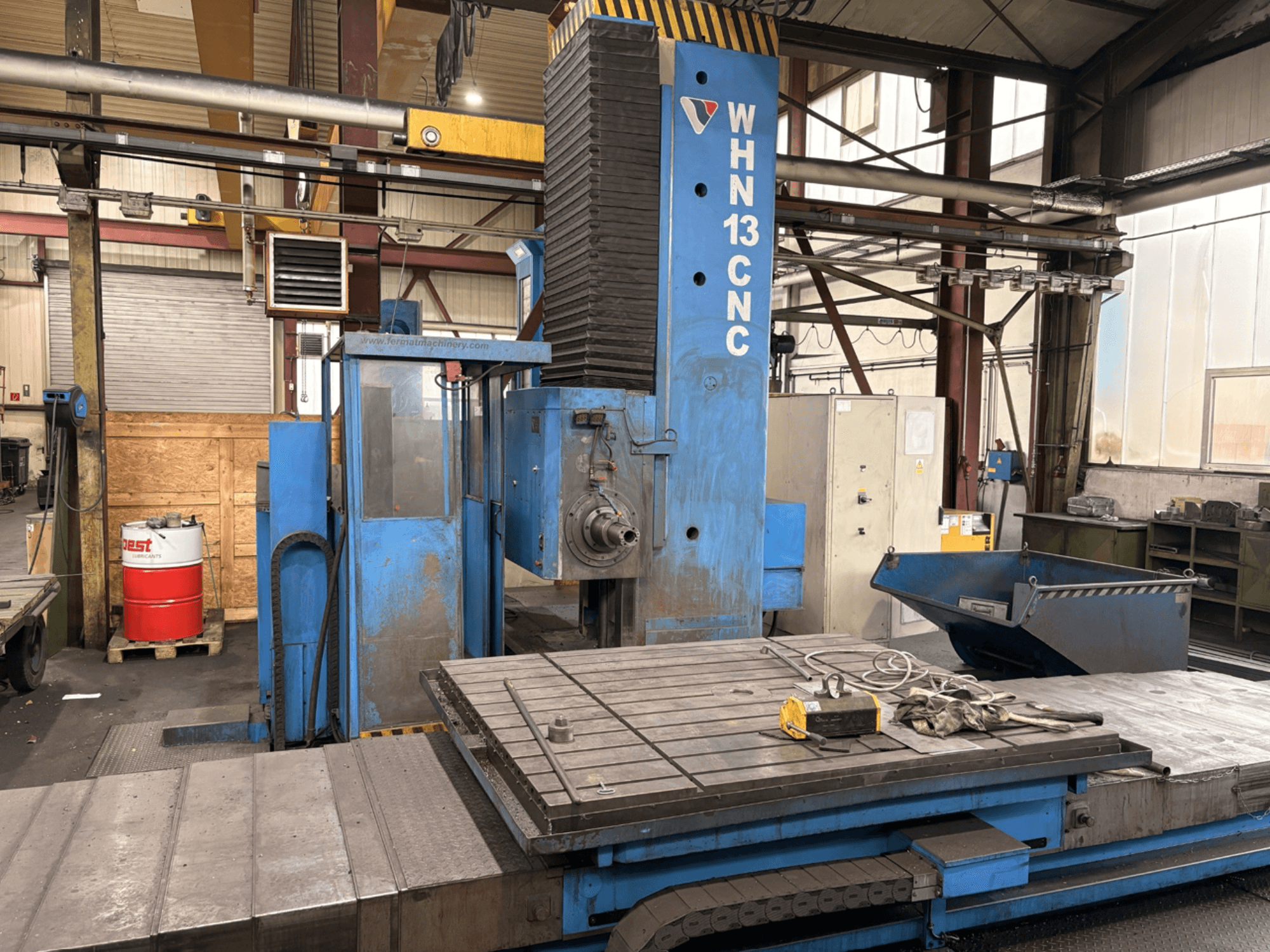 Centro di lavorazione orizzontale CNC FERMAT WHN 13.8, vista frontale che mostra il pannello di controllo, il piano di lavoro e i dettagli dell'ambiente industriale.