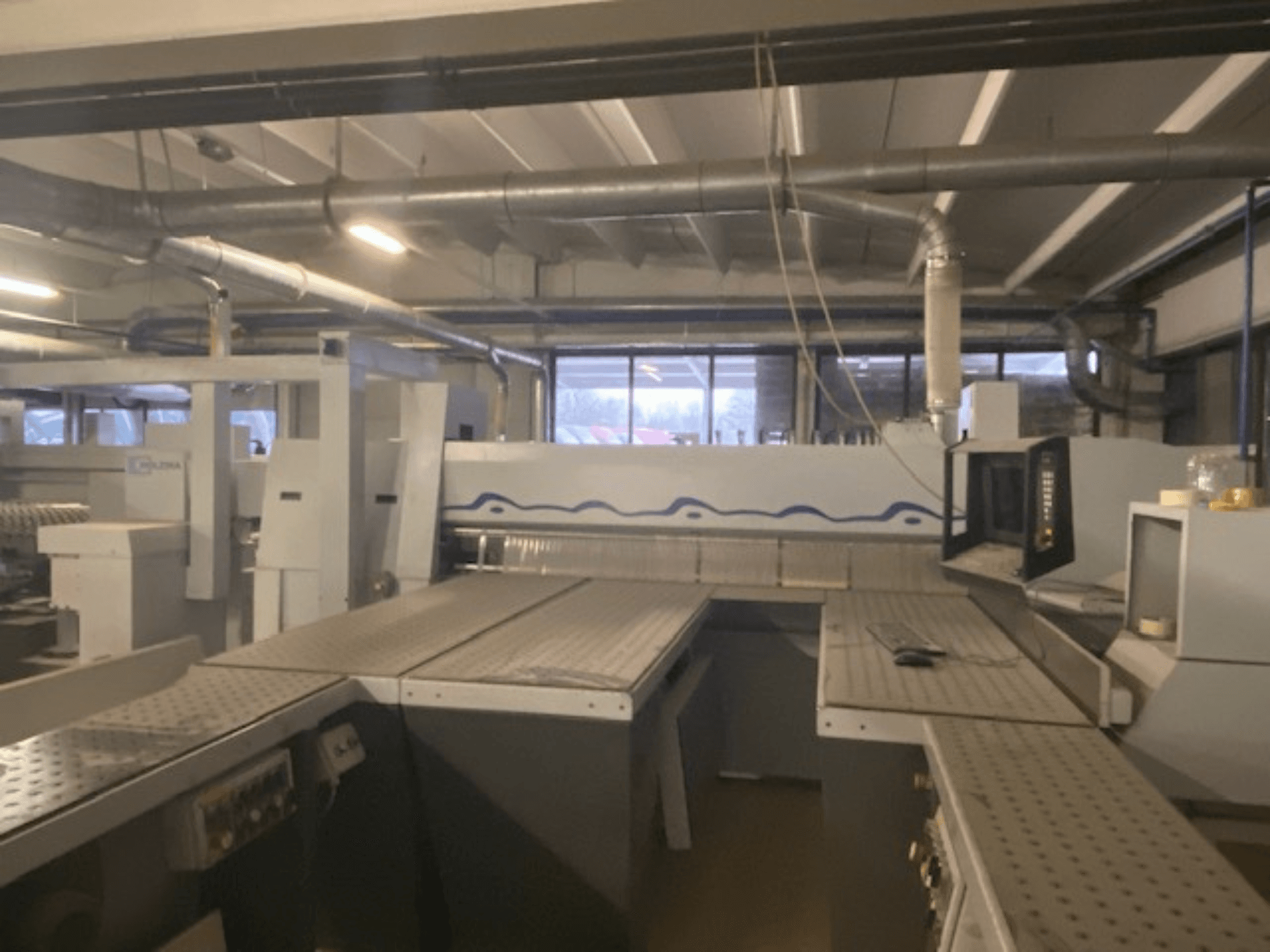 Spazio di lavoro industriale caratterizzato da un macchinario con pannello di controllo, visto da un'angolazione frontale elevata.