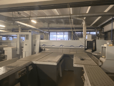 Spazio di lavoro industriale caratterizzato da un macchinario con pannello di controllo, visto da un'angolazione frontale elevata.