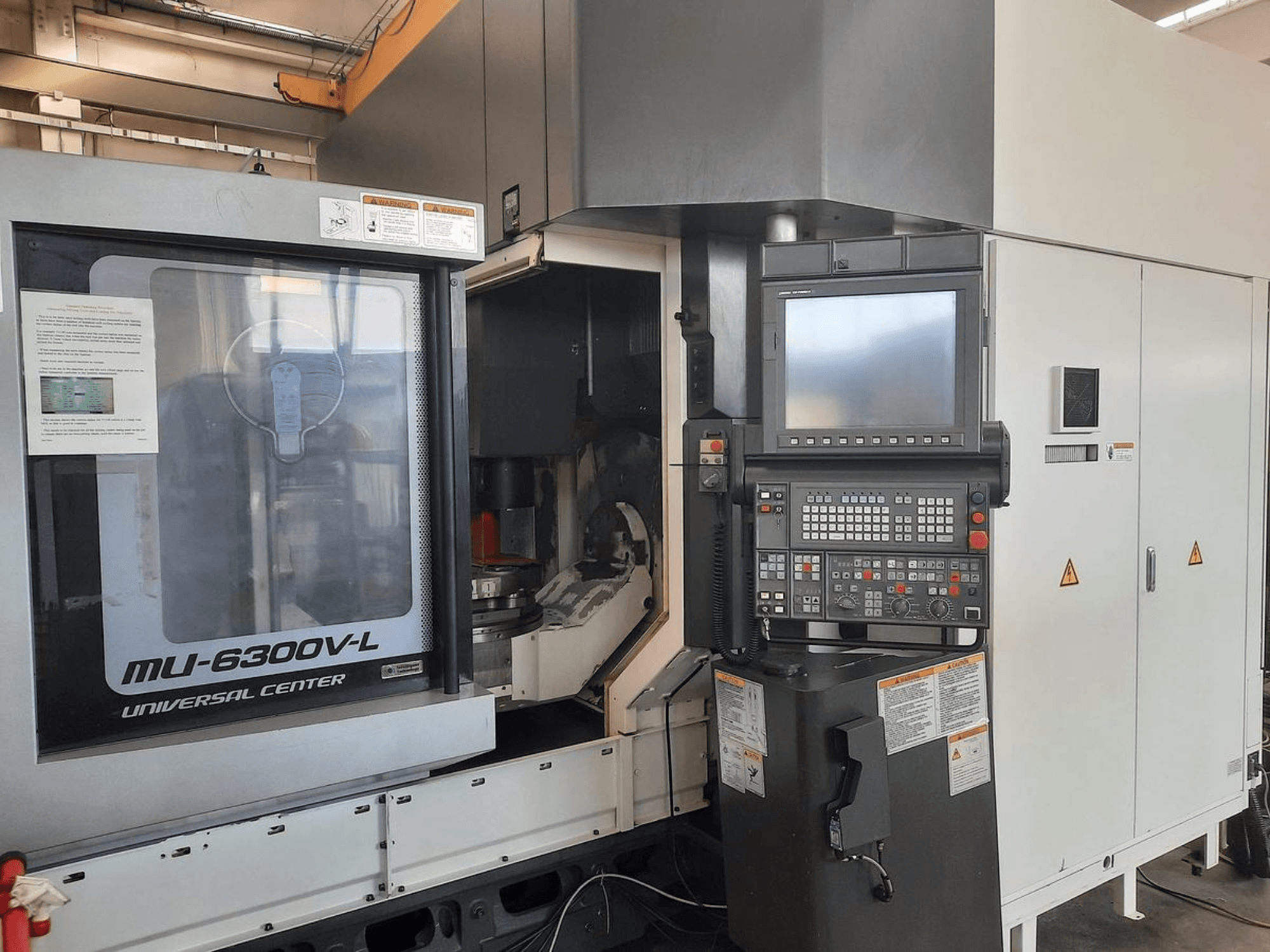 La macchina MU-6300V-L Universal Center vista dal davanti, con pannello di controllo, schermo e istruzioni operative visibili.