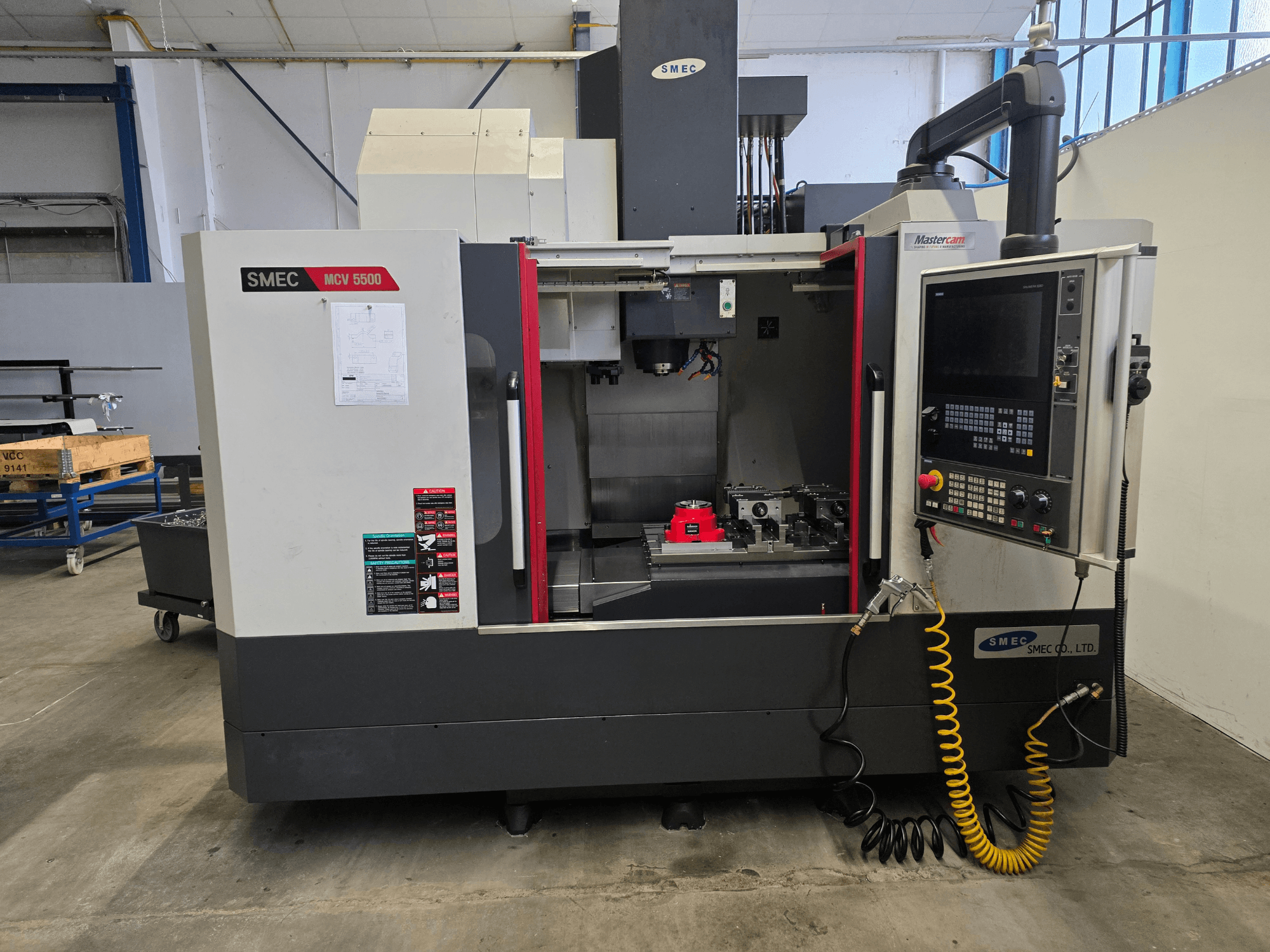 Centro di lavorazione verticale SMEC MCV 5500, vista frontale, con il pannello di controllo e l'interno della macchina con gli utensili.
