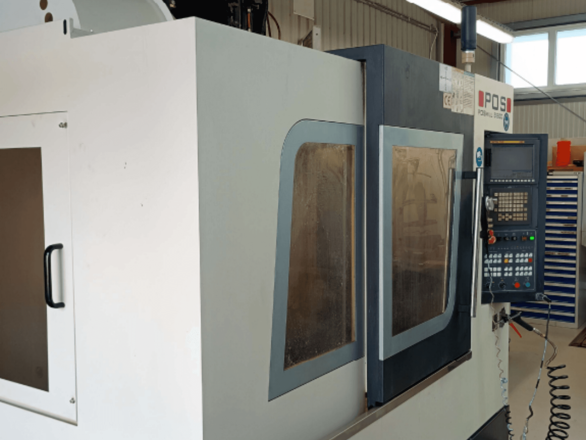 Centro di lavorazione verticale POSmill B 800 visto frontalmente, con pannelli di comando e finestrini in vetro di sicurezza.