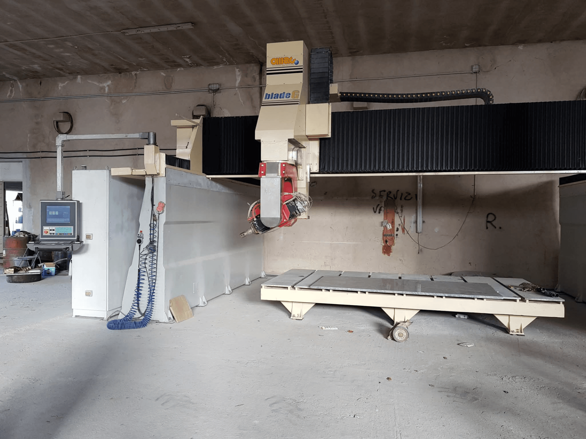 Fresatrice a portale OMAG Blade G in un'officina, vista frontale con pannello di controllo e grande banco di fresatura visibili.