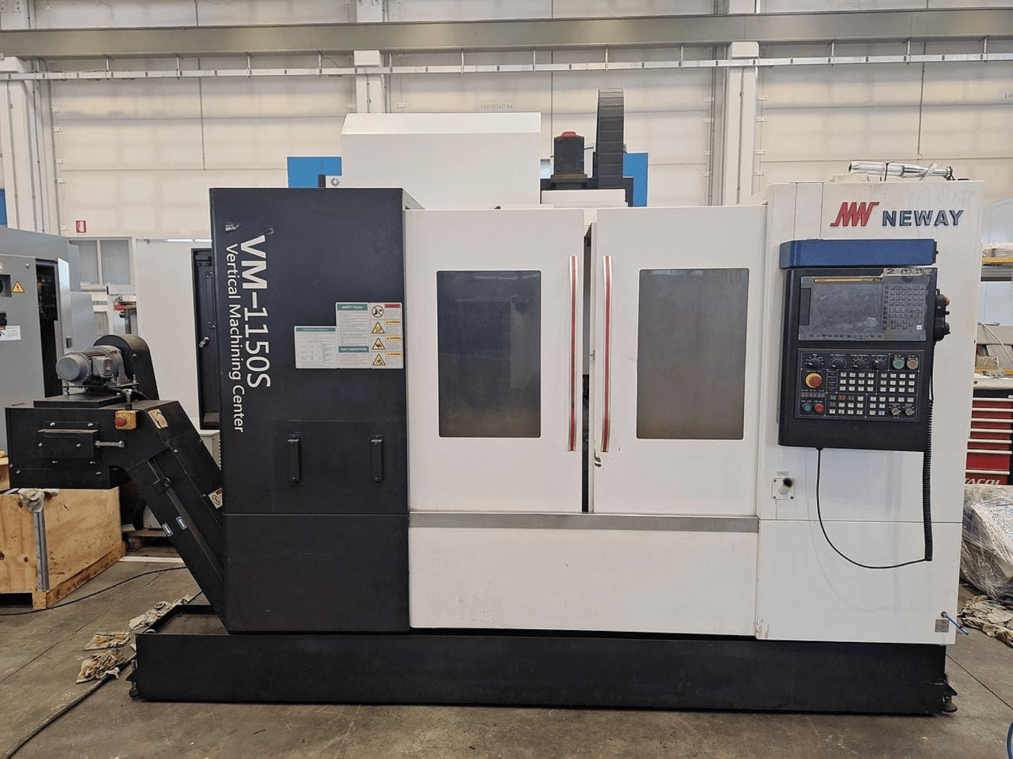 Centro di lavoro verticale Neway VM-1150S, vista frontale che mostra il pannello di controllo, le porte e le etichette di sicurezza.