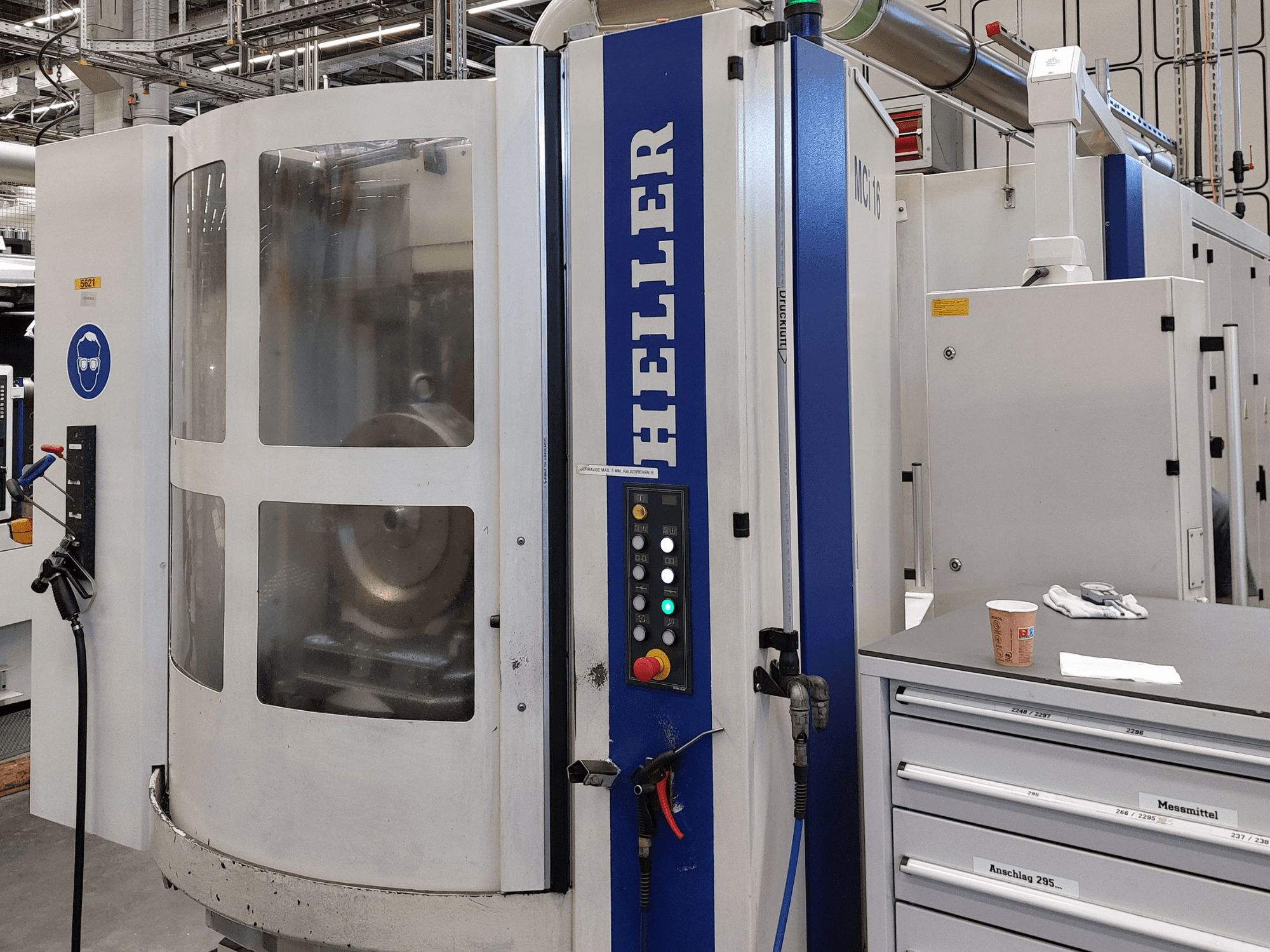 Centro di lavorazione orizzontale Heller MCI 16 visto di profilo, con pannello di controllo, finestra trasparente e area di lavoro circostante.