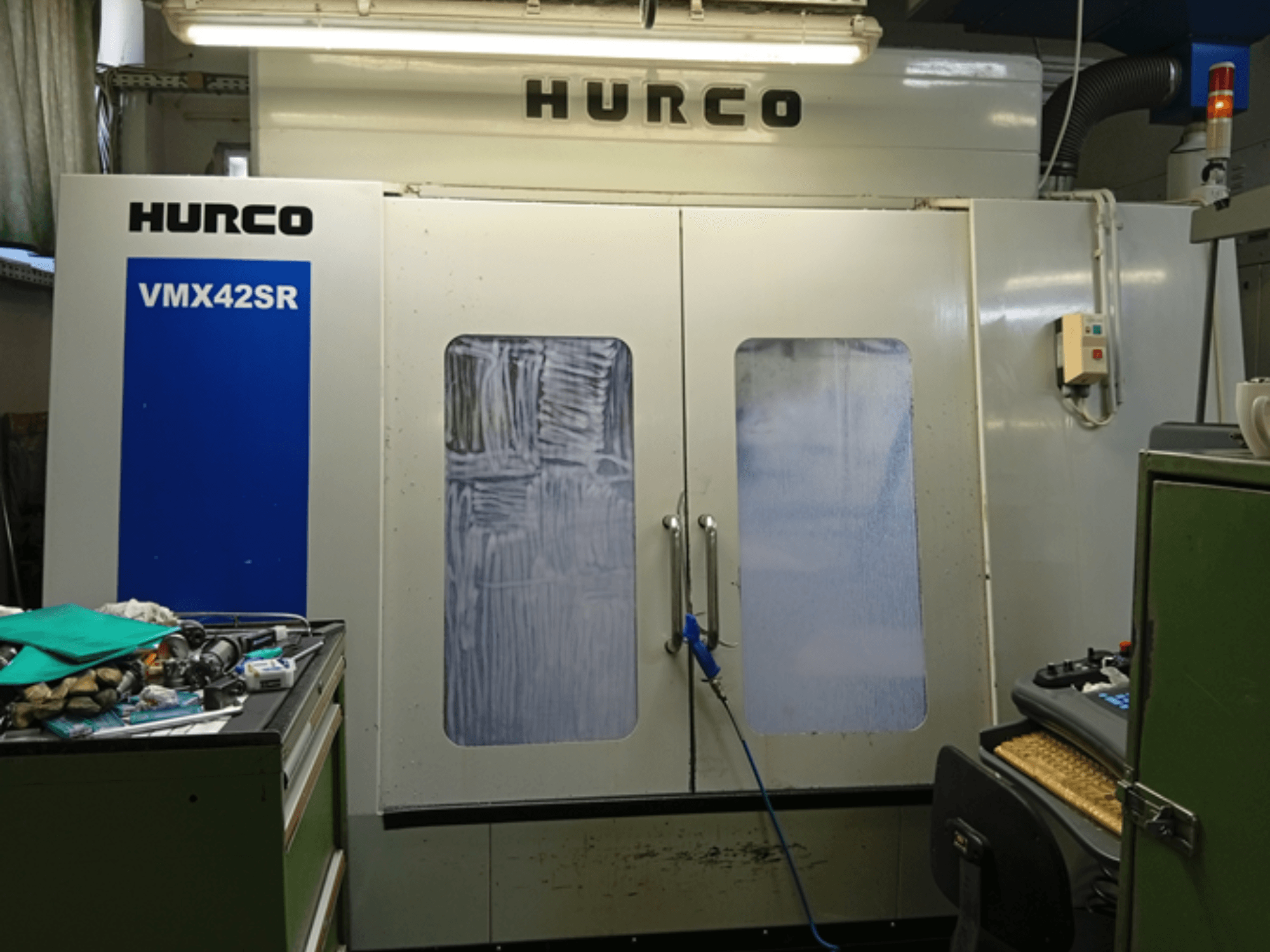 Centro di lavoro verticale Hurco VMX 42SR in vista frontale, con pannello blu, interfaccia di controllo e spazio di lavoro pulito.