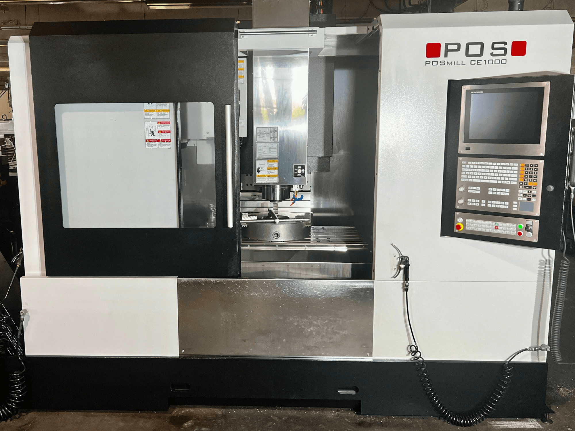 Vista frontale del centro di lavorazione verticale POSmill CE1000, con in primo piano il pannello di controllo, la finestra e le superfici metalliche.