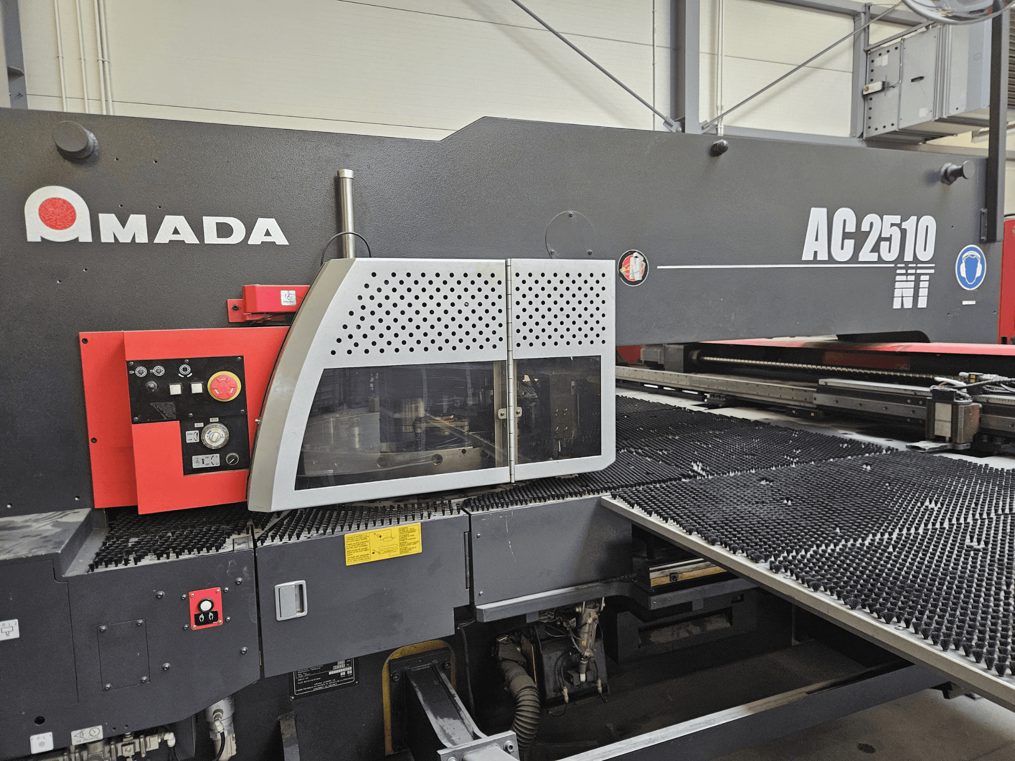 Macchina da taglio laser Amada AC2510 NT, vista frontale, con pannello di controllo con manopole, pulsanti e copertura di sicurezza.