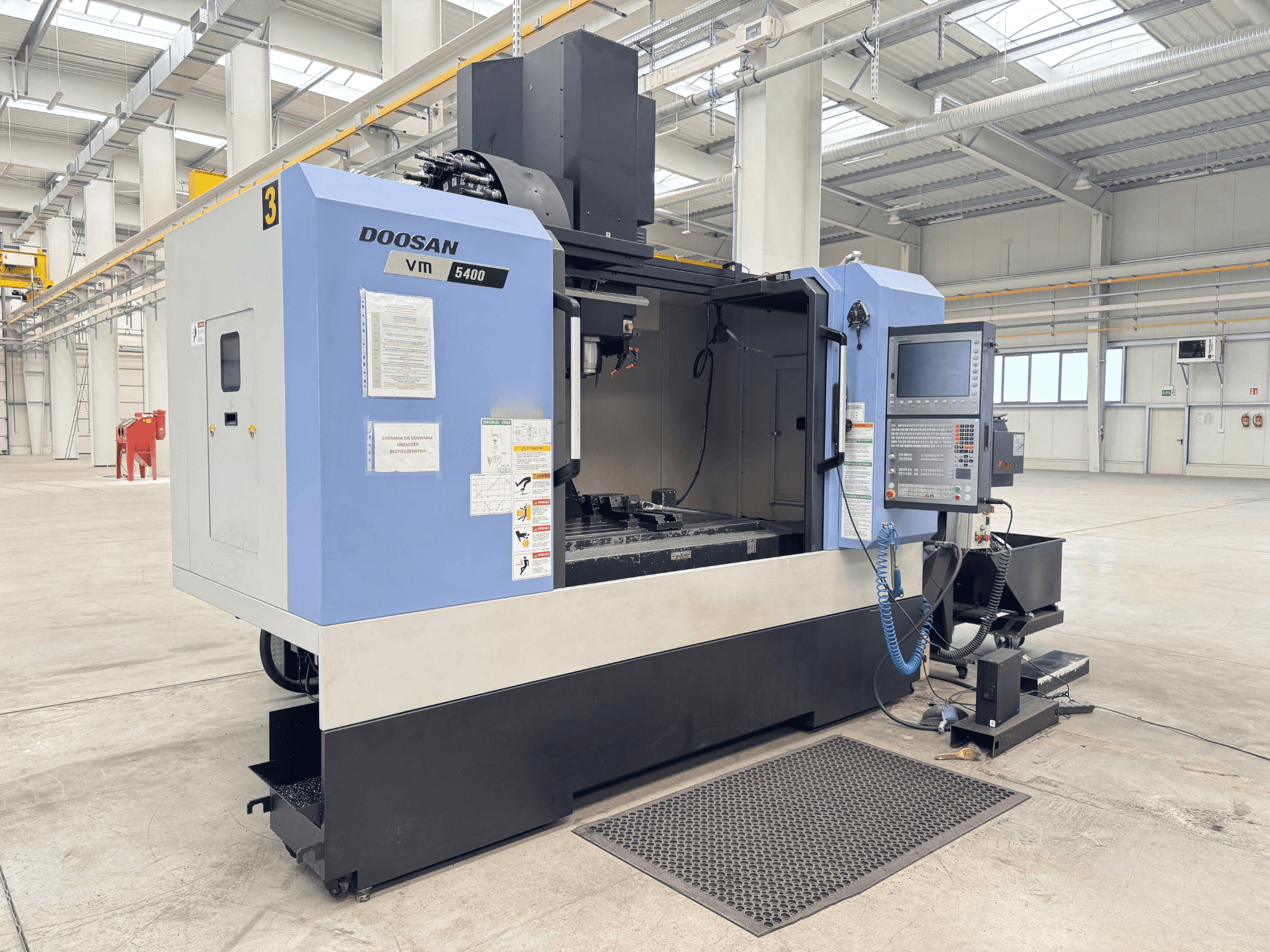 Centro di lavoro verticale DOOSAN VM 5400, vista frontale che mostra il pannello di controllo e l'area di lavoro in un ampio ambiente industriale.