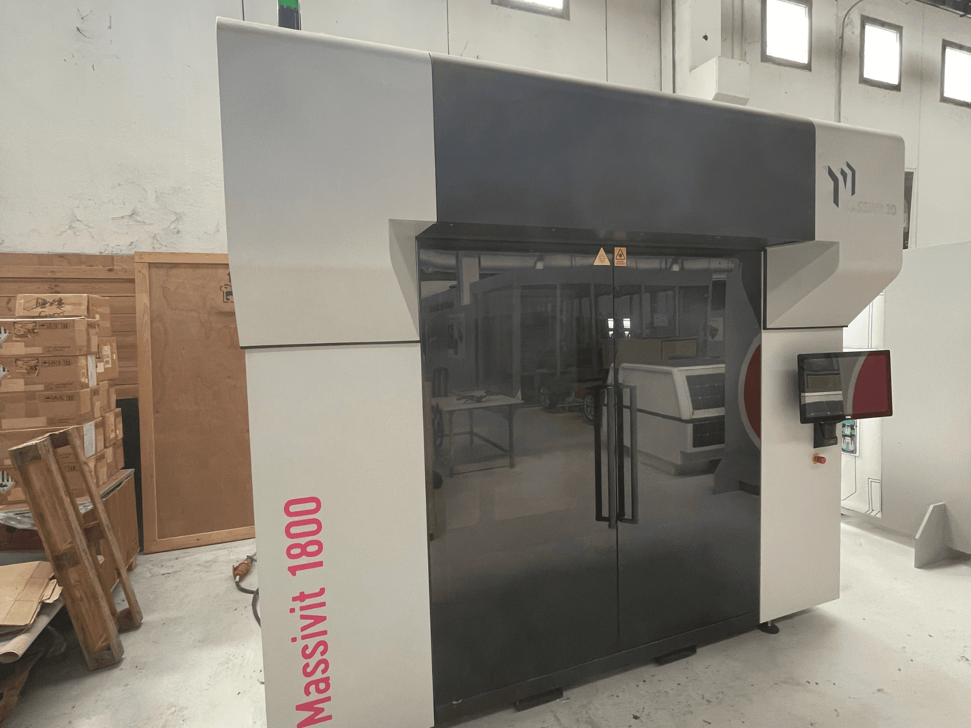 MASSIVIT: la stampante 3D per plastica Massivit 1800, raffigurata in una vista laterale, dotata di touchscreen e caratterizzata da un elegante design in bianco e nero.
