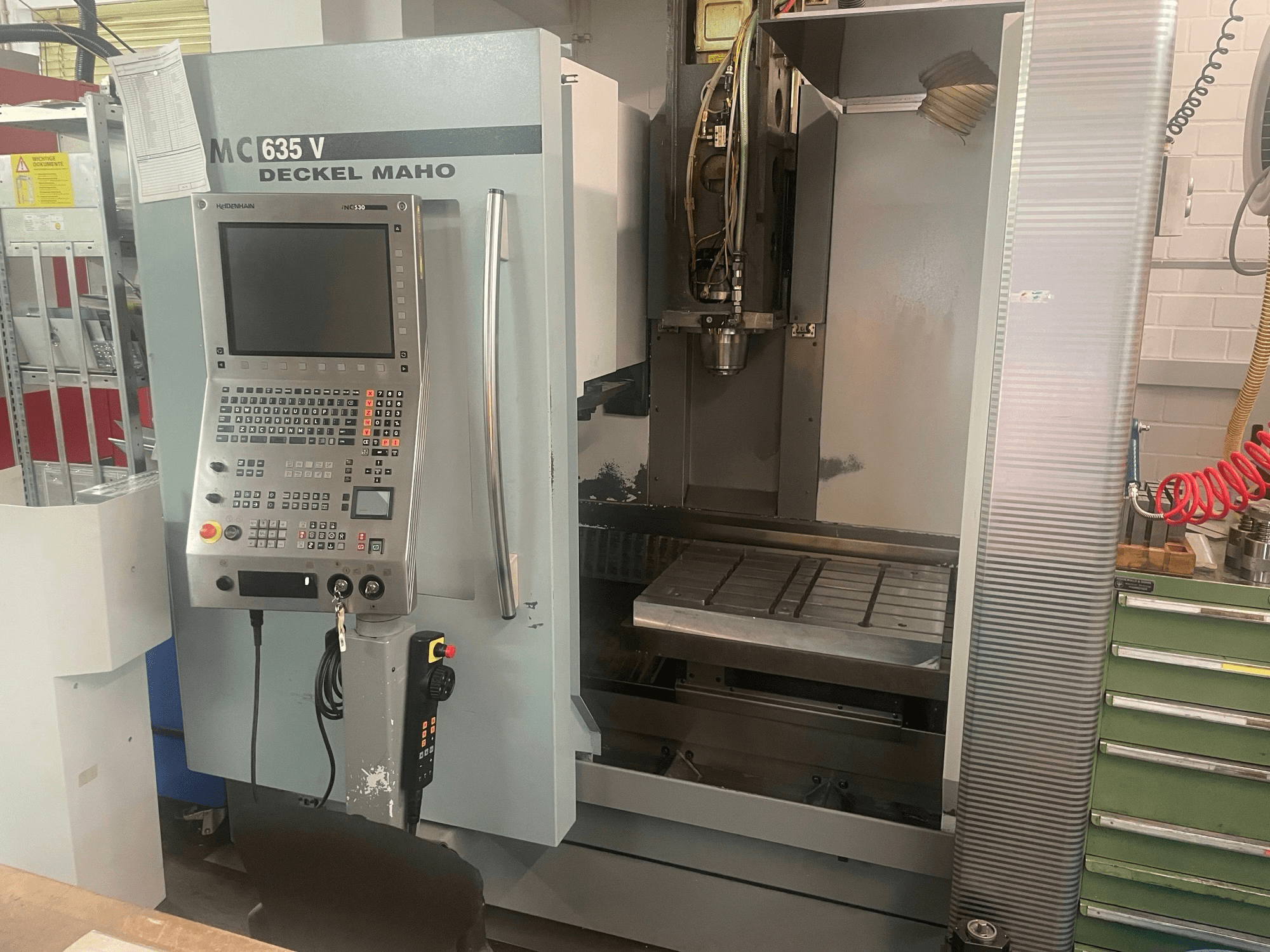 Vista frontale del centro di lavorazione verticale DECKEL MAHO DMC 635 V con pannello di comando e area di lavoro aperta, che mostra la testa portautensili e il basamento.