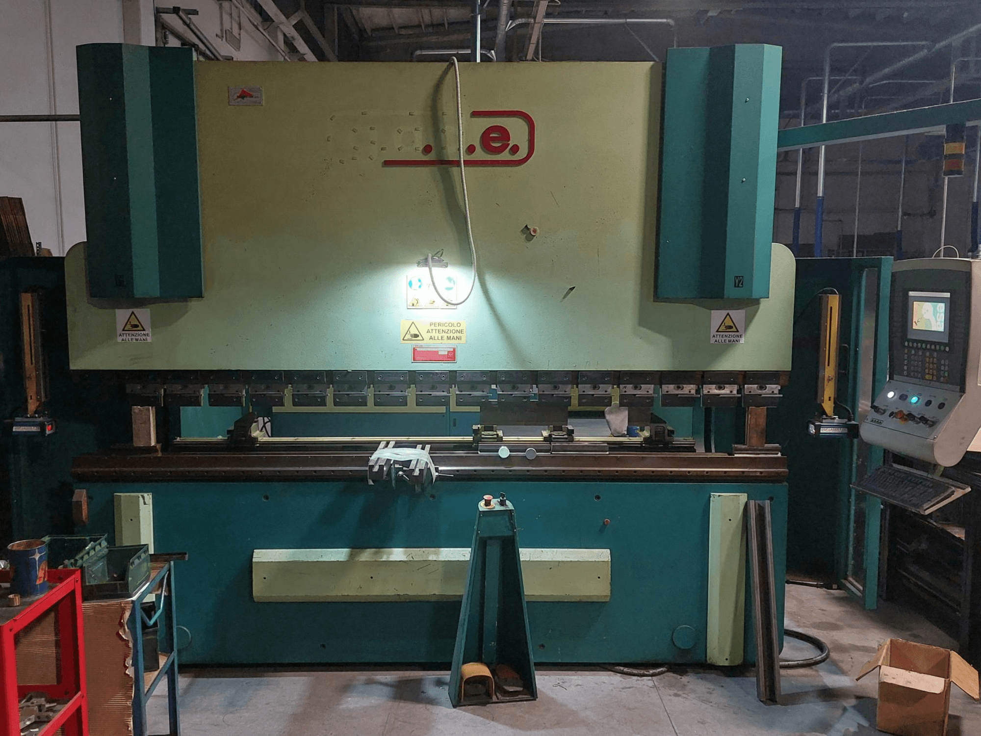 Vista frontale della pressa piegatrice Gade PS-C 3120, con pannello di controllo, segnaletica di sicurezza e area di lavoro con utensili e materiali.