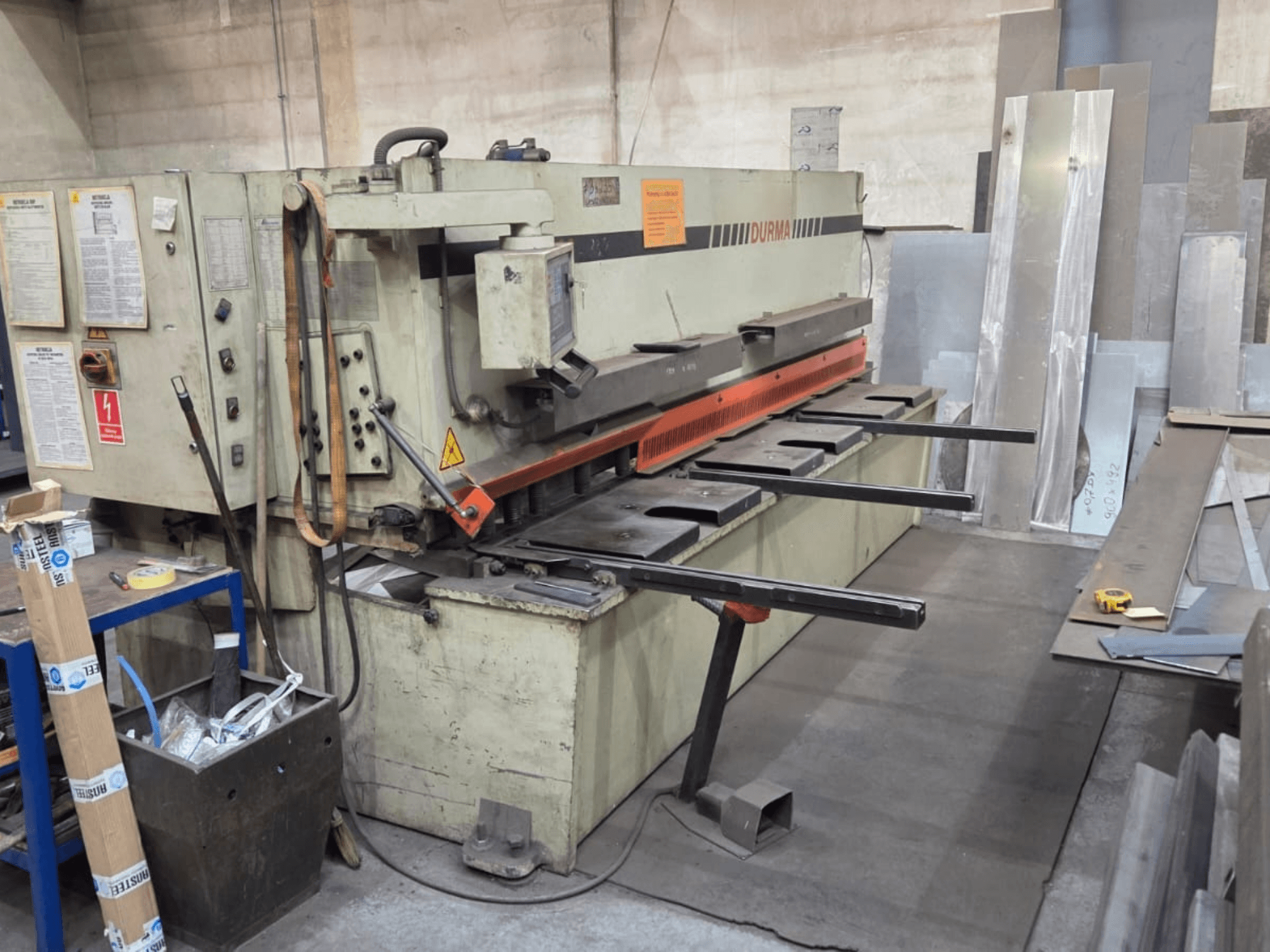 Cesoia idraulica Durma SB 3060, vista frontale, con comandi, lama di taglio e lamiere nell'area di lavoro.