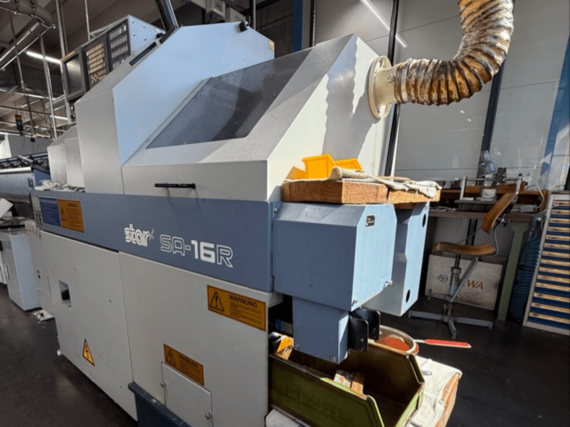 La macchina Stark SA-16R vista frontalmente, con scarico affusolato e area di lavoro con utensili gialli ed etichette di avvertimento.