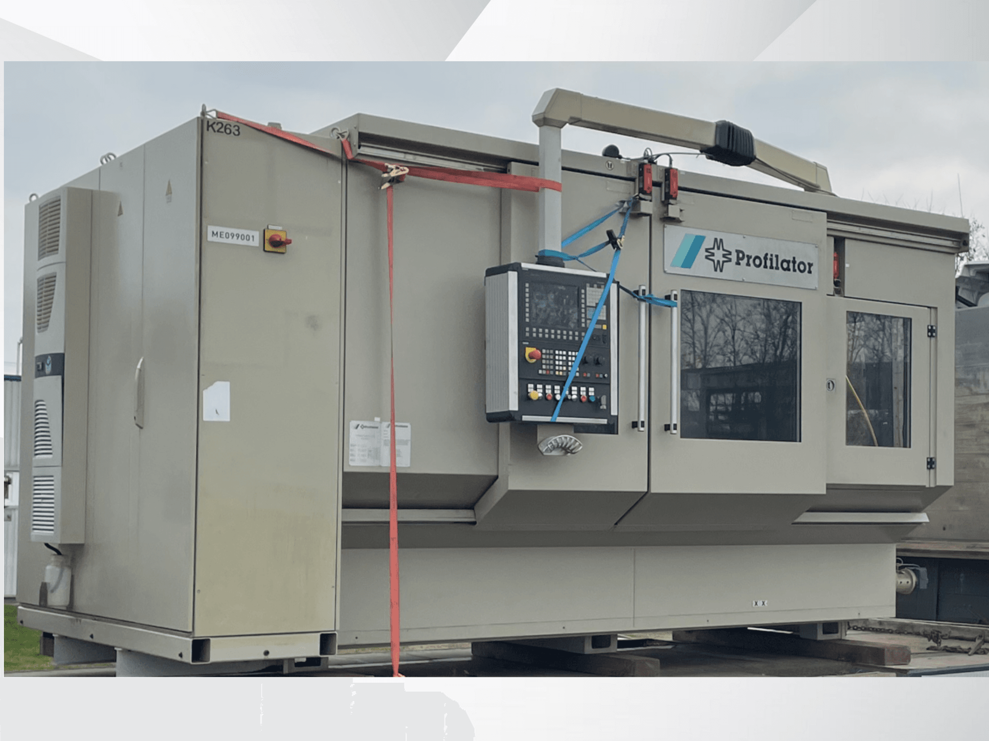 Macchina profilatrice in vista laterale, con pannello di controllo, etichette di sicurezza e reggette di protezione, su una piattaforma di legno.