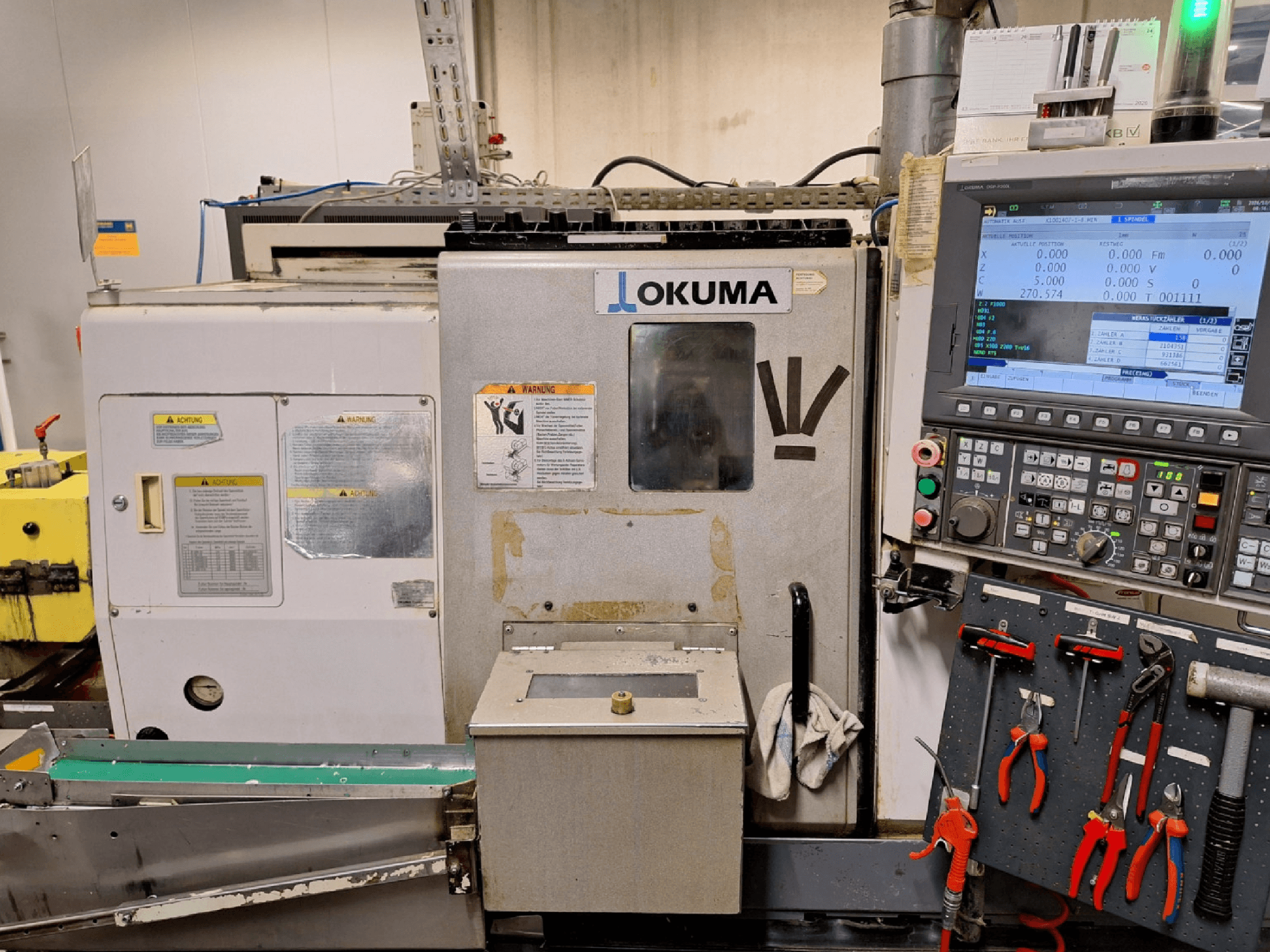 Tornio orizzontale Okuma LB200-MW, vista frontale, con pannello di controllo e utensili visibili sul lato.