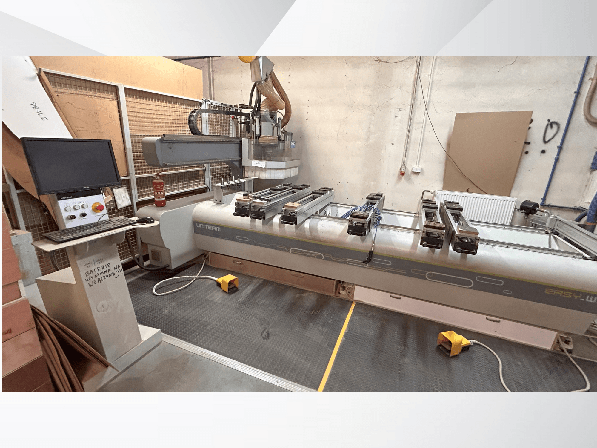 Vista frontale di una macchina CNC UNITEM EASY-W, con pannello di controllo, monitor e pezzi bloccati sul tavolo di lavoro.