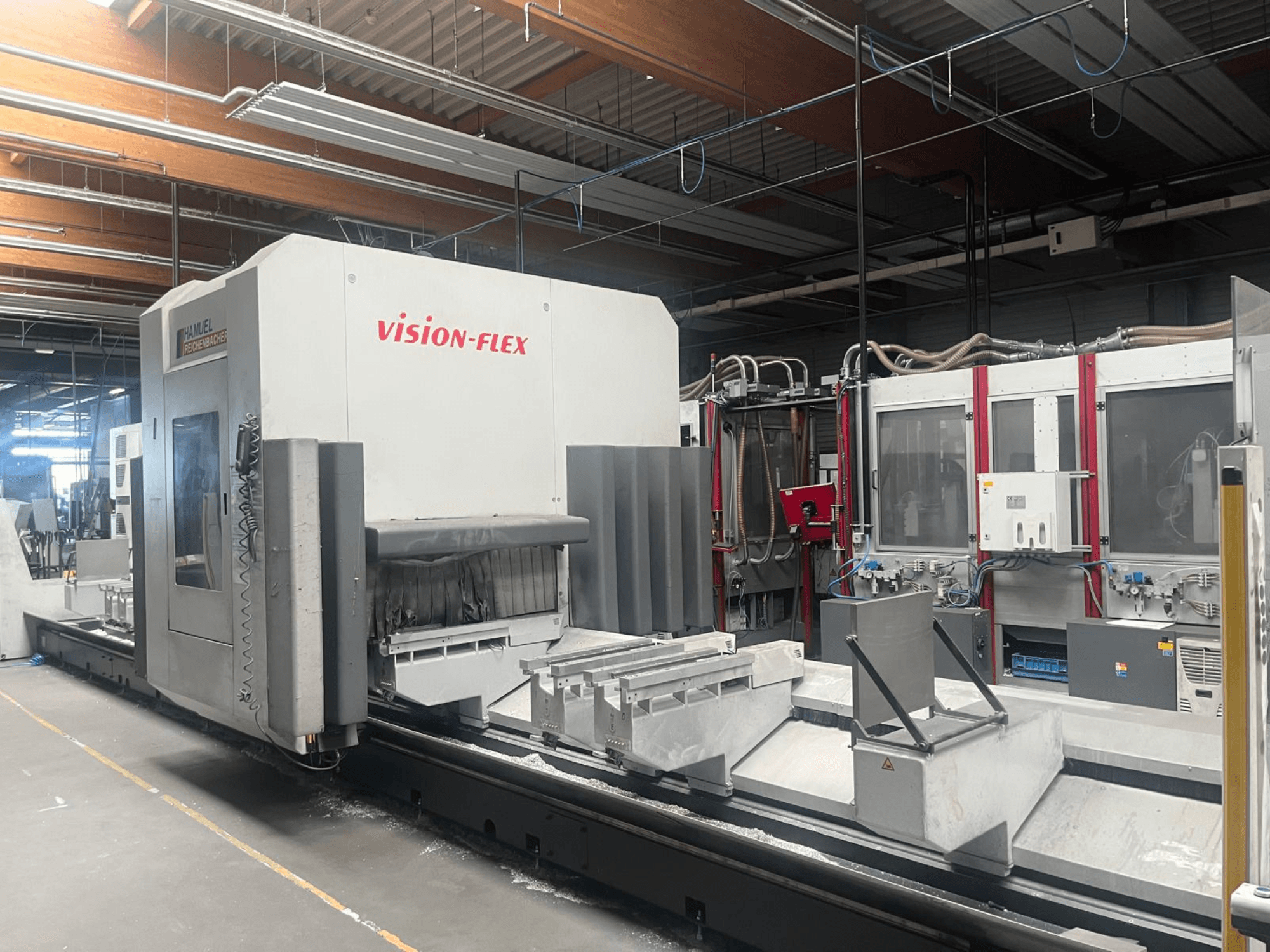 Centro di lavorazione verticale Hamuel Reichenbacher Vision Flex: vista laterale che mostra l'area di lavoro e i comandi in un ambiente industriale.
