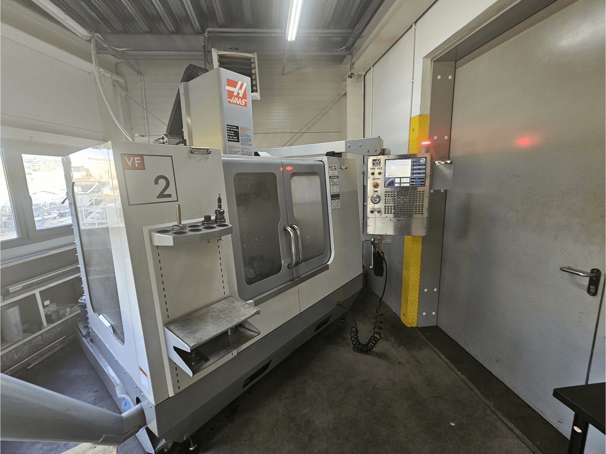 Fresatrice CNC Haas VF-2, vista frontale, che mostra il pannello di controllo, i portautensili e una finestra trasparente sull'area di lavoro.