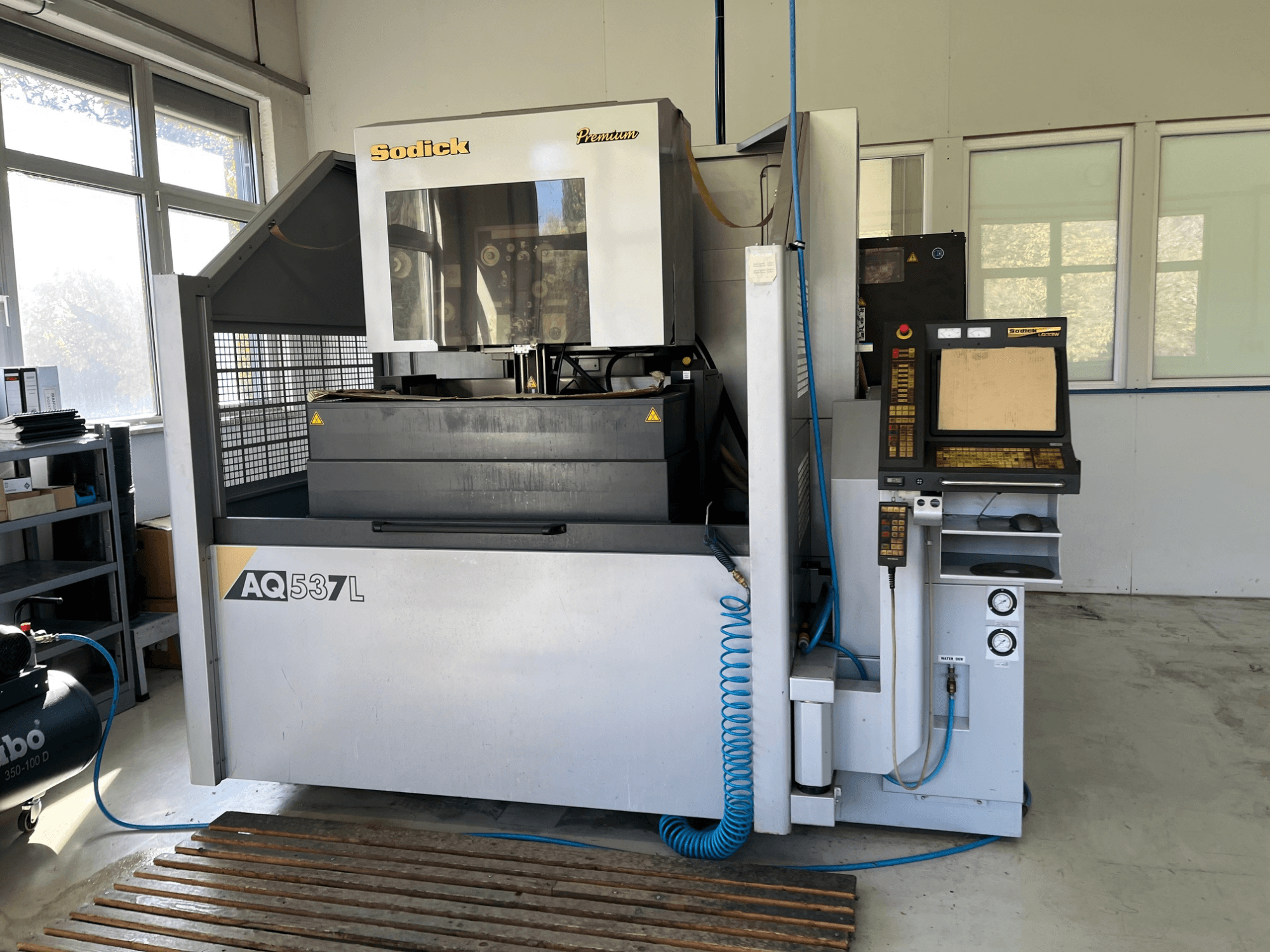 Macchina per elettroerosione (EDM) Sodick AQ537L in vista frontale, con pannello di controllo, linee di raffreddamento dell'acqua e area di lavoro.