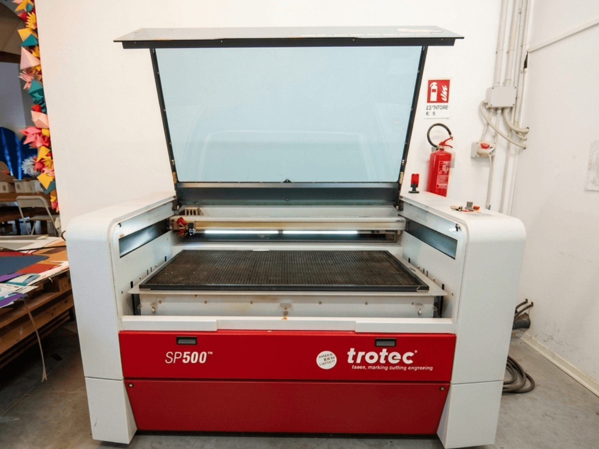 Macchina per incisione laser Trotec SP500 C200 in vista frontale, con il coperchio aperto che mostra l'area di lavoro e i comandi.