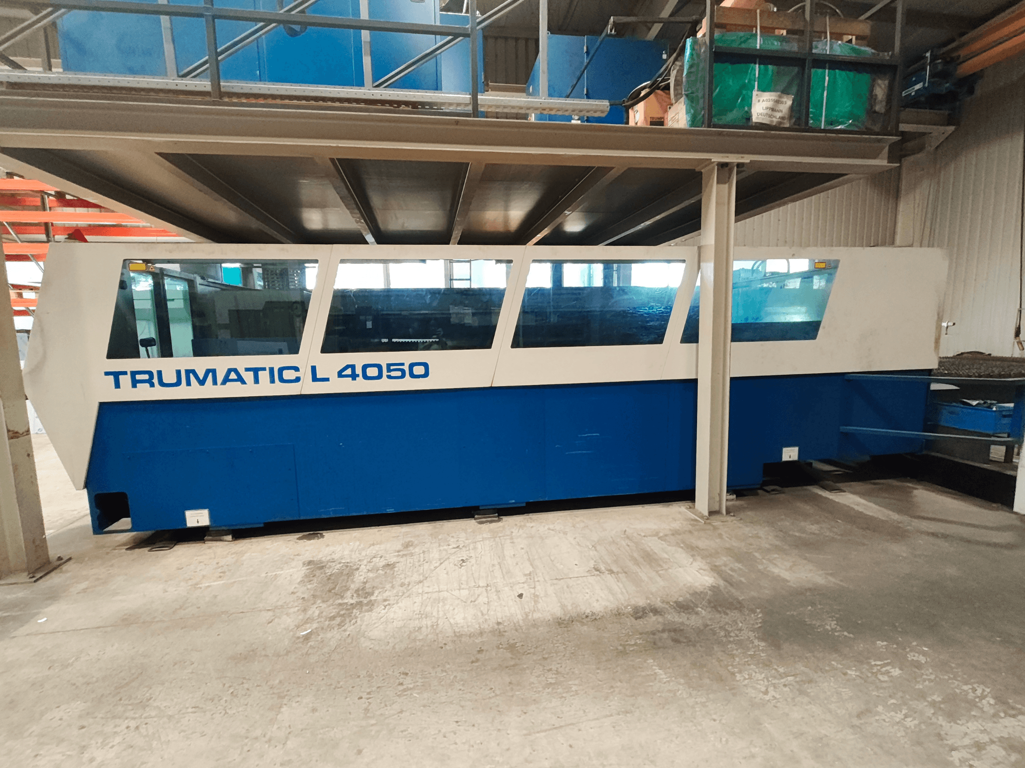 Macchina per il taglio laser a CO₂ TRUMPF TruLaser 450 vista di profilo, caratterizzata da un design blu e bianco, con pannello di controllo e area di lavoro ben visibili.