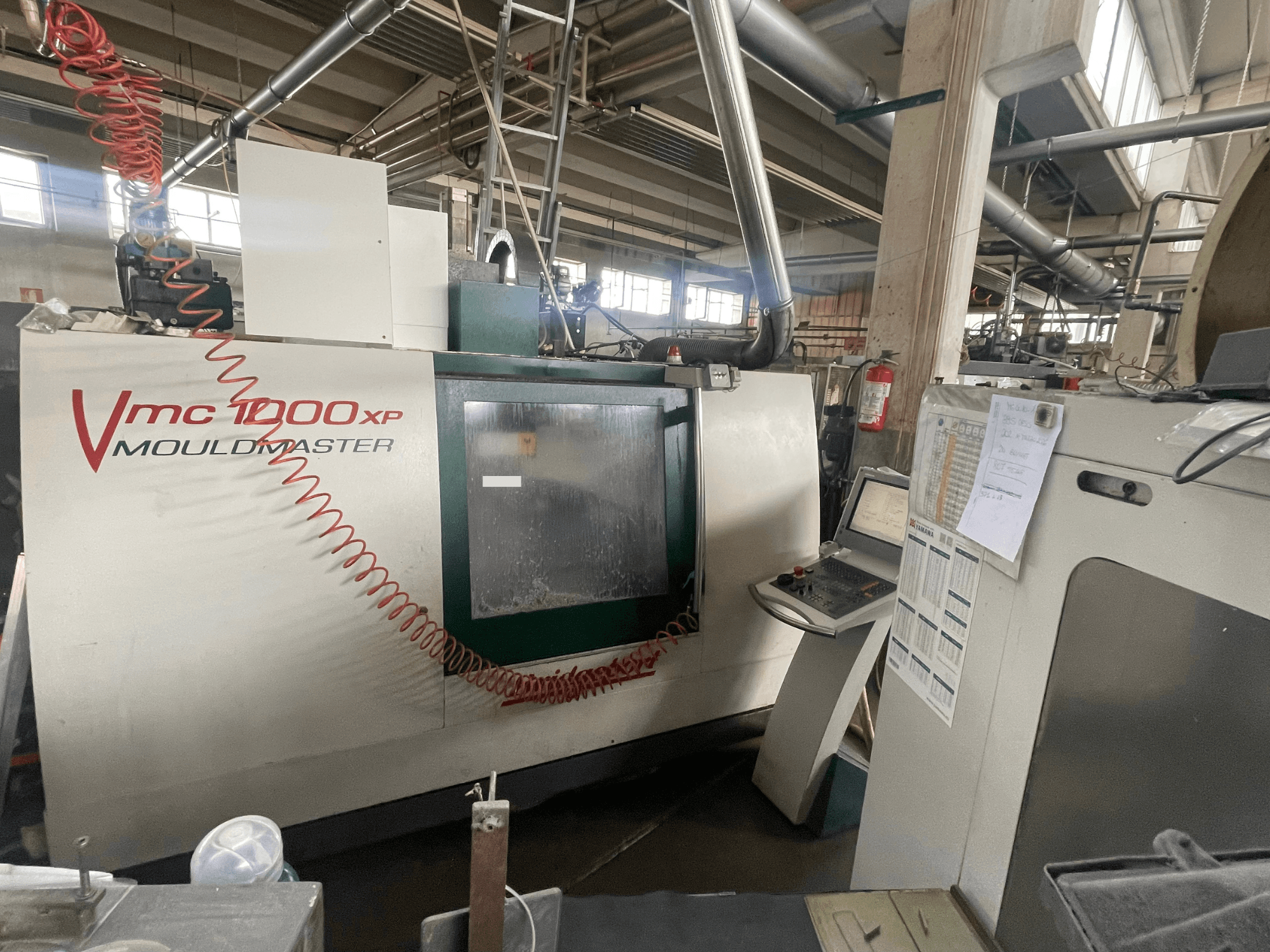 Centro di lavorazione verticale Bridgeport VMC 1000, vista frontale, con pannello di controllo e dettagli della macchina in un ambiente industriale.