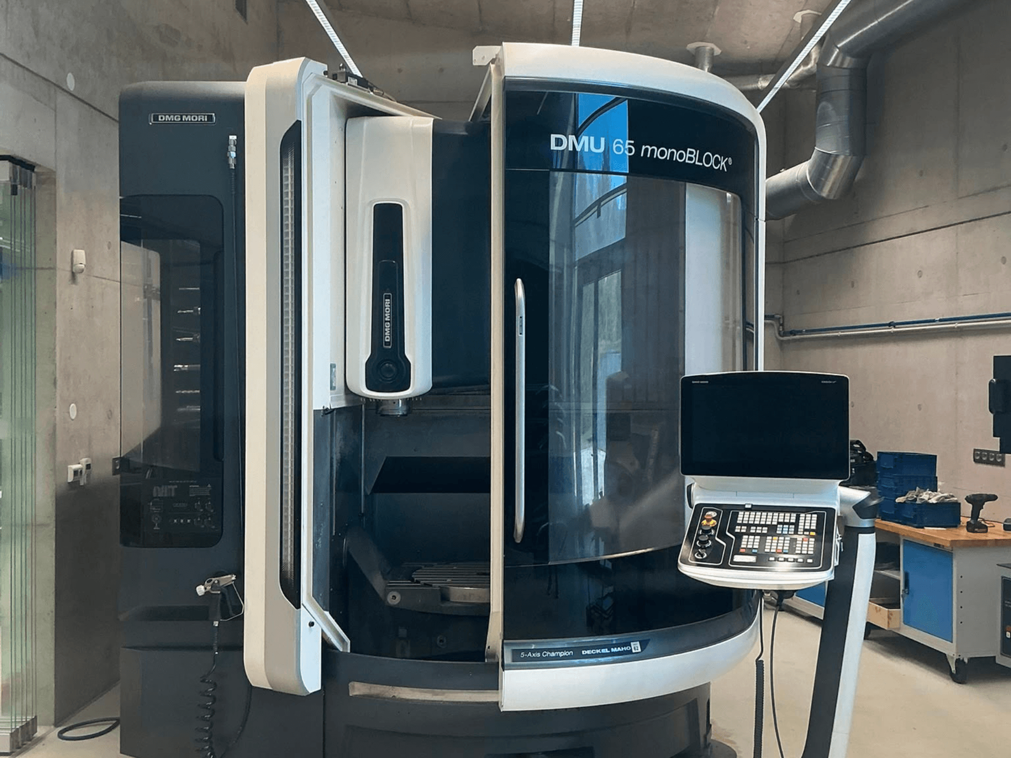 Centro di lavorazione verticale DMG MORI DMU 65 monoBLOCK, vista frontale, che mostra il pannello di controllo e i dettagli della macchina in un ambiente di officina.