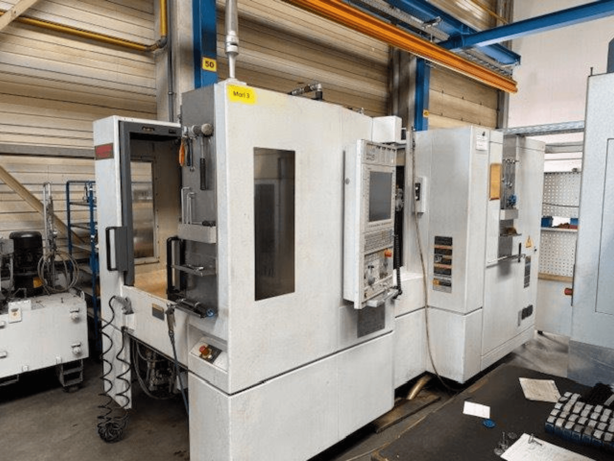 Vista frontale di un centro di lavoro orizzontale MORI SEIKI NH4000 DCG con porta aperta e pannello di controllo visibile, che mostra lo spazio operativo.