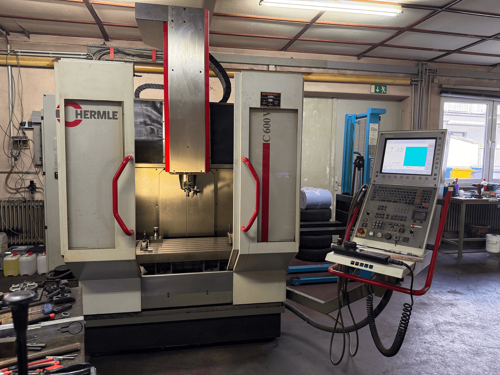 La fresatrice CNC Hermle C 600 vista frontalmente, con un pannello di controllo dotato di numerosi pulsanti e un'ampia area di lavoro.