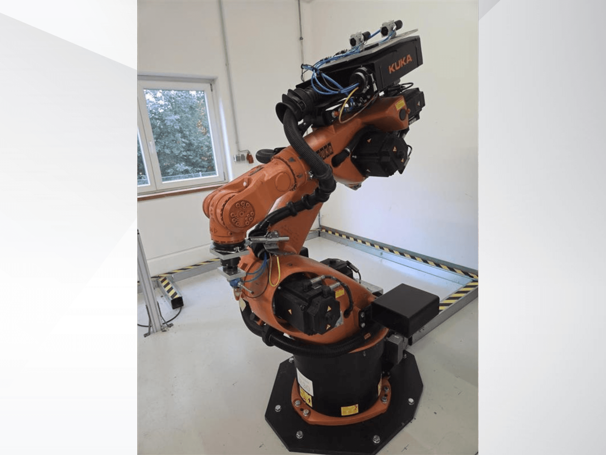 Braccio robotico KUKA KR60 HA visto di profilo, con in evidenza i giunti meccanici e il cablaggio su una base industriale.