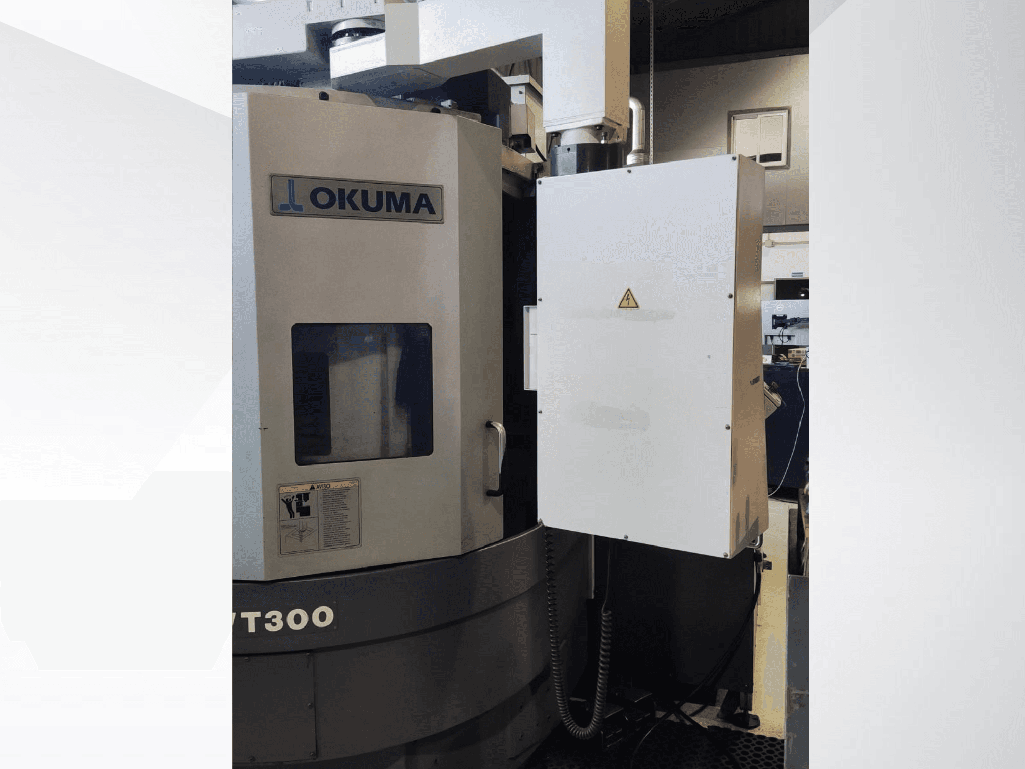 Tornio verticale Okuma LVT300, vista frontale, che mostra il pannello di controllo e le caratteristiche di sicurezza etichettate.