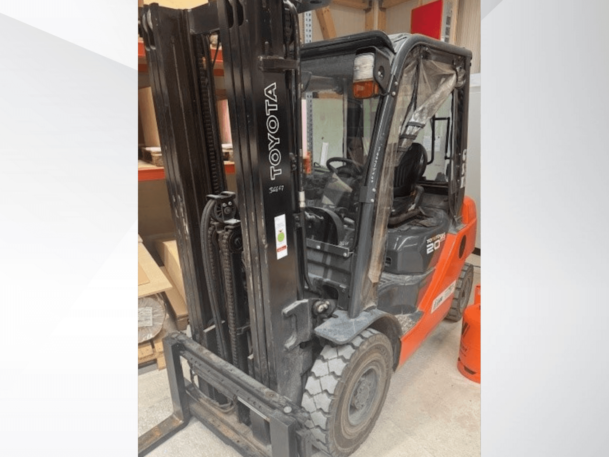 Carrello elevatore Toyota 20 visto frontalmente, con montante nero, cabina trasparente e serbatoio del propano arancione accanto.