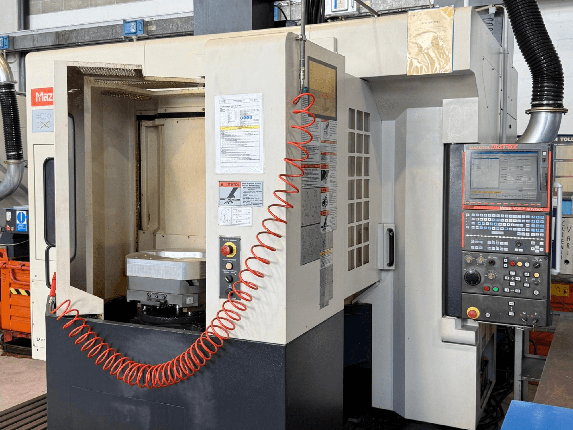 Centro di lavorazione verticale Mazak VARIAXIS I 500 visto frontalmente, con in primo piano il pannello di controllo, il portapezzi e l'area di stoccaggio degli utensili.
