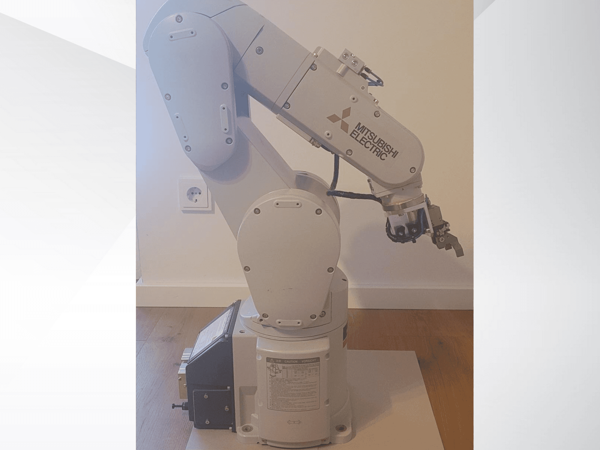 Braccio robotico Mitsubishi Electric, vista laterale, con pinza e pannello di controllo dettagliato sulla base per le impostazioni operative.