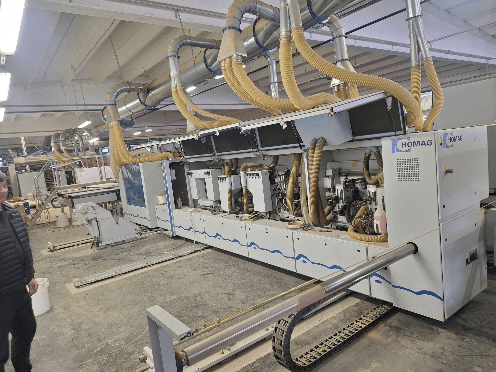 Macchina per la lavorazione del legno HOMAG in un ambiente industriale, vista frontale che mostra i mandrini multipli e il sistema di aspirazione della polvere.