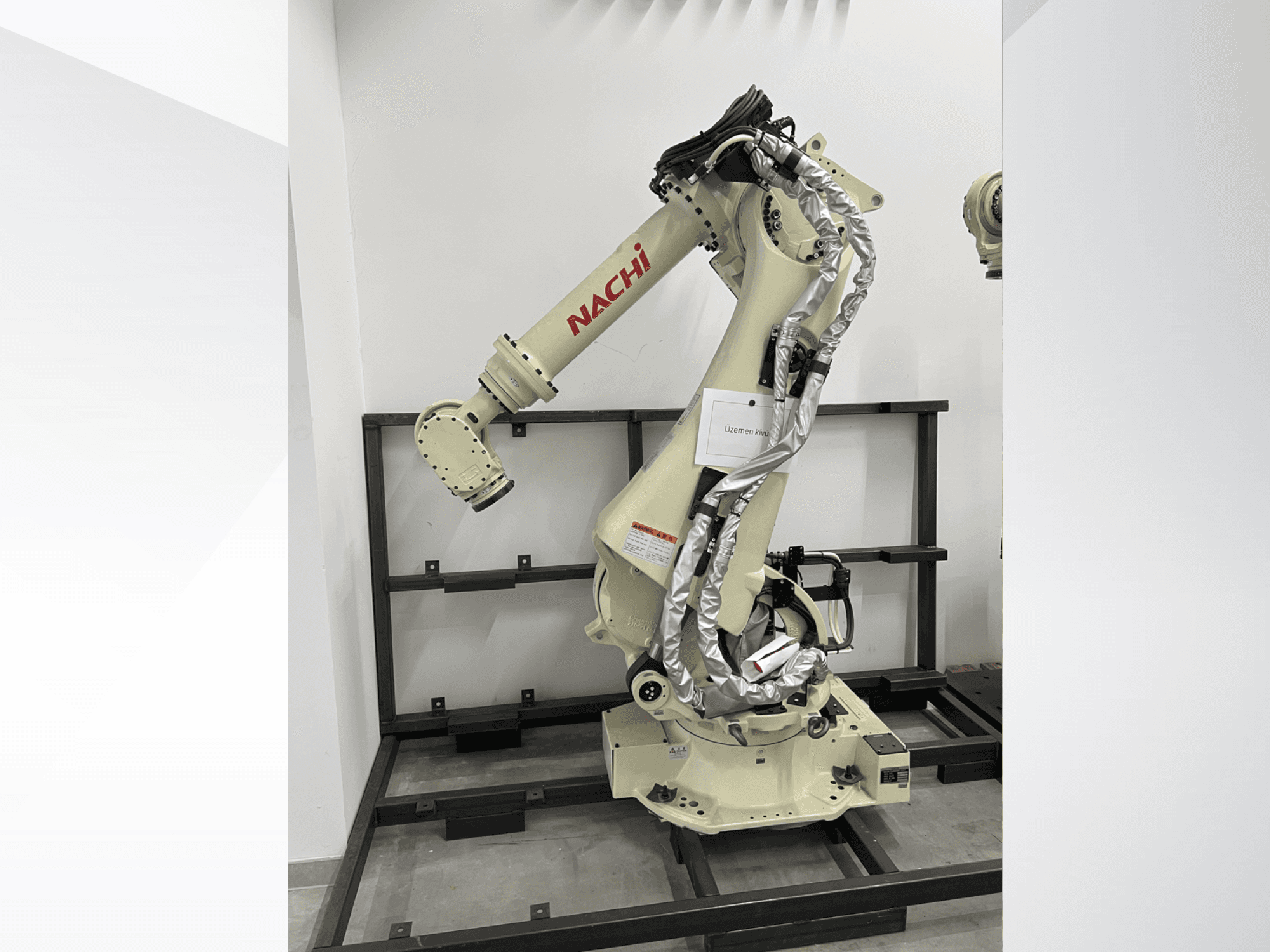 Braccio robotico NACHI SRA166-01 in vista laterale, dotato di giunti flessibili, cavi collegati e montato su un telaio di protezione.